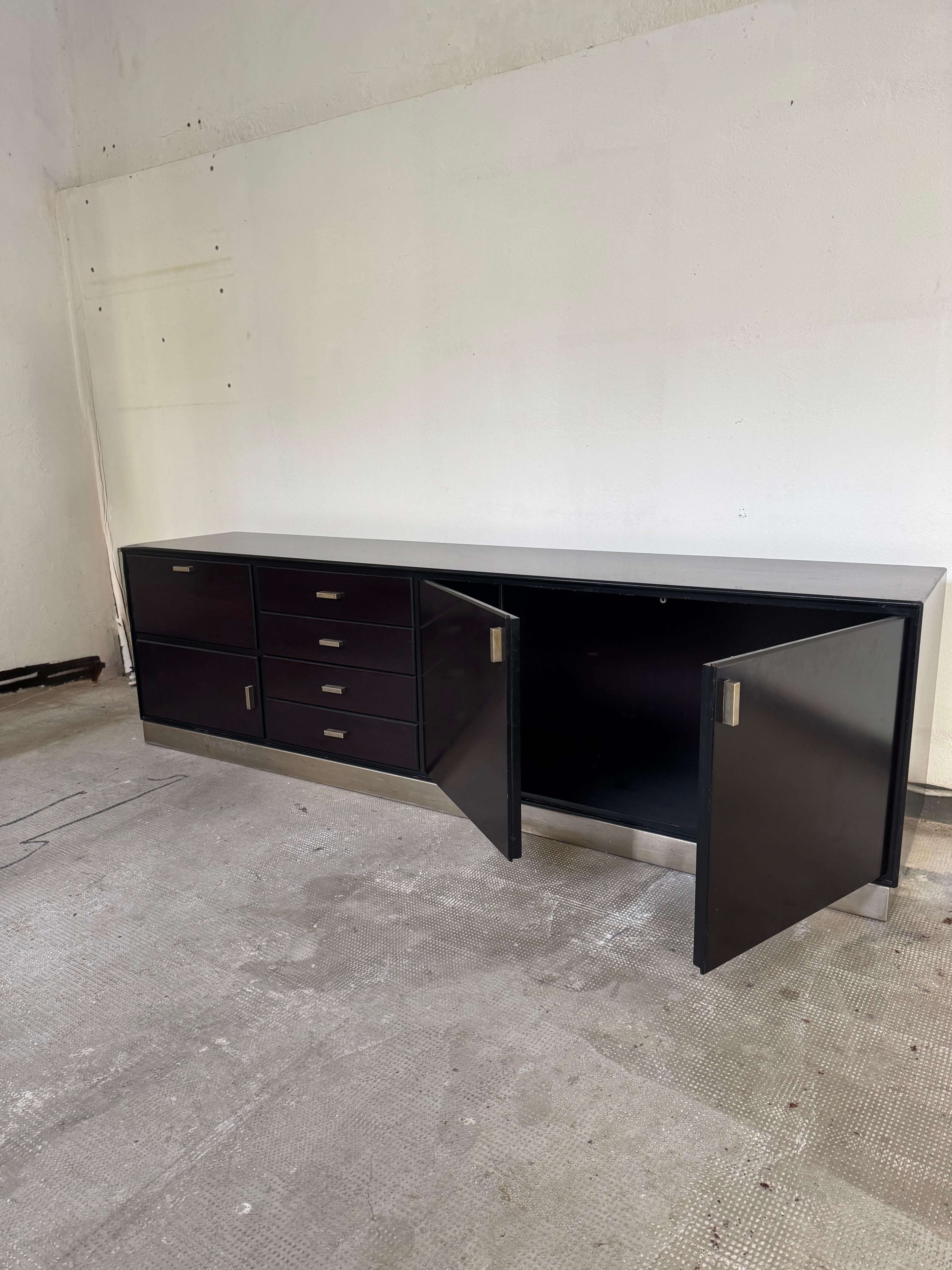 Elegante credenza disegnata da Gianni Moscatelli per Formanova negli anni ’70, espressione del design modernista italiano. La struttura è realizzata in legno con finitura naturale, mentre la base e i dettagli sono in acciaio cromato, conferendo un