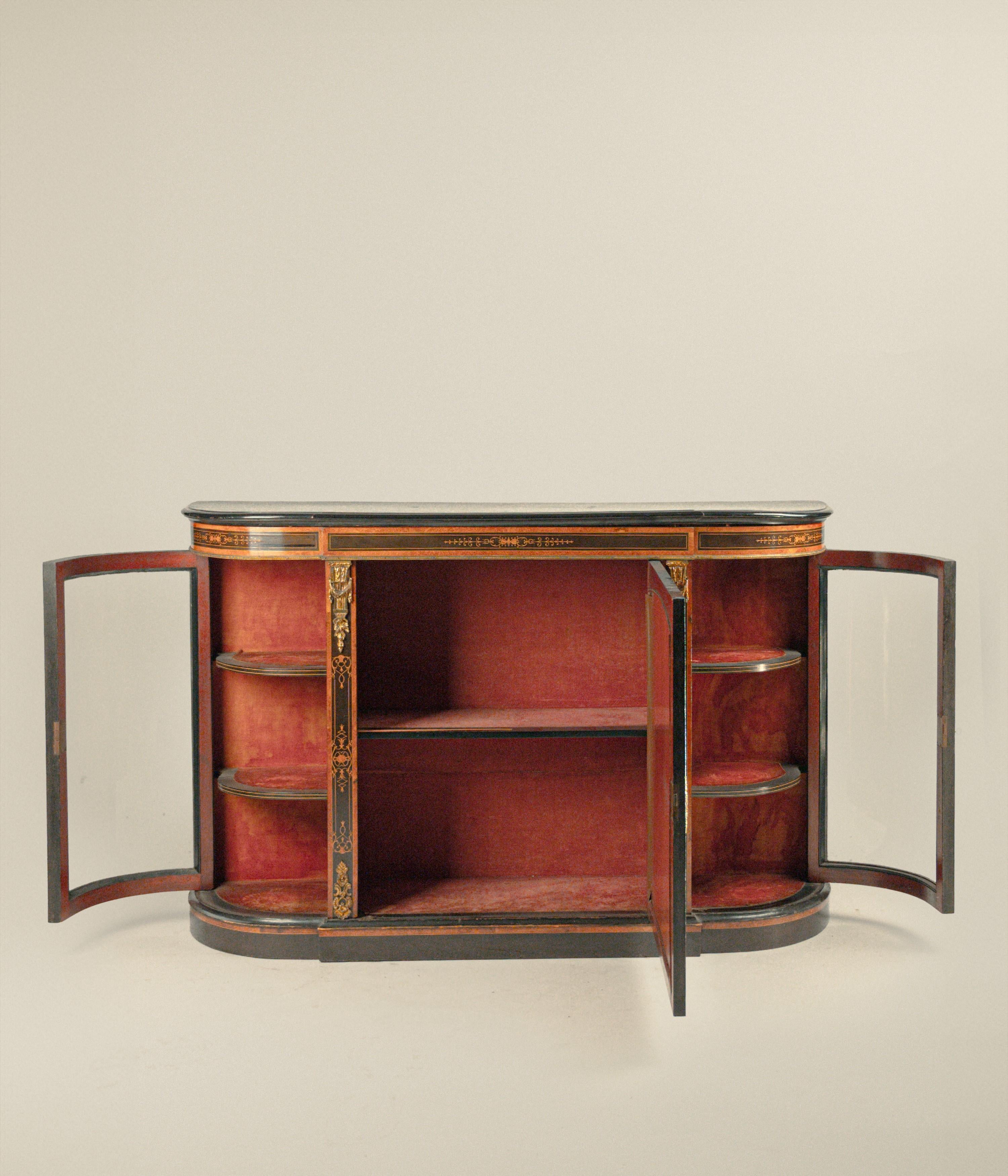 Credenza in legno ebanizzato e intarsiata in legni diversi, Inghilterra,  XIX secolo, corpo stondato con ante laterali a vetri e anta centrale con medaglione intarsiato a fitti girali che si ripetono sulle lesene ornate da fregi in bronzo dorato, cm