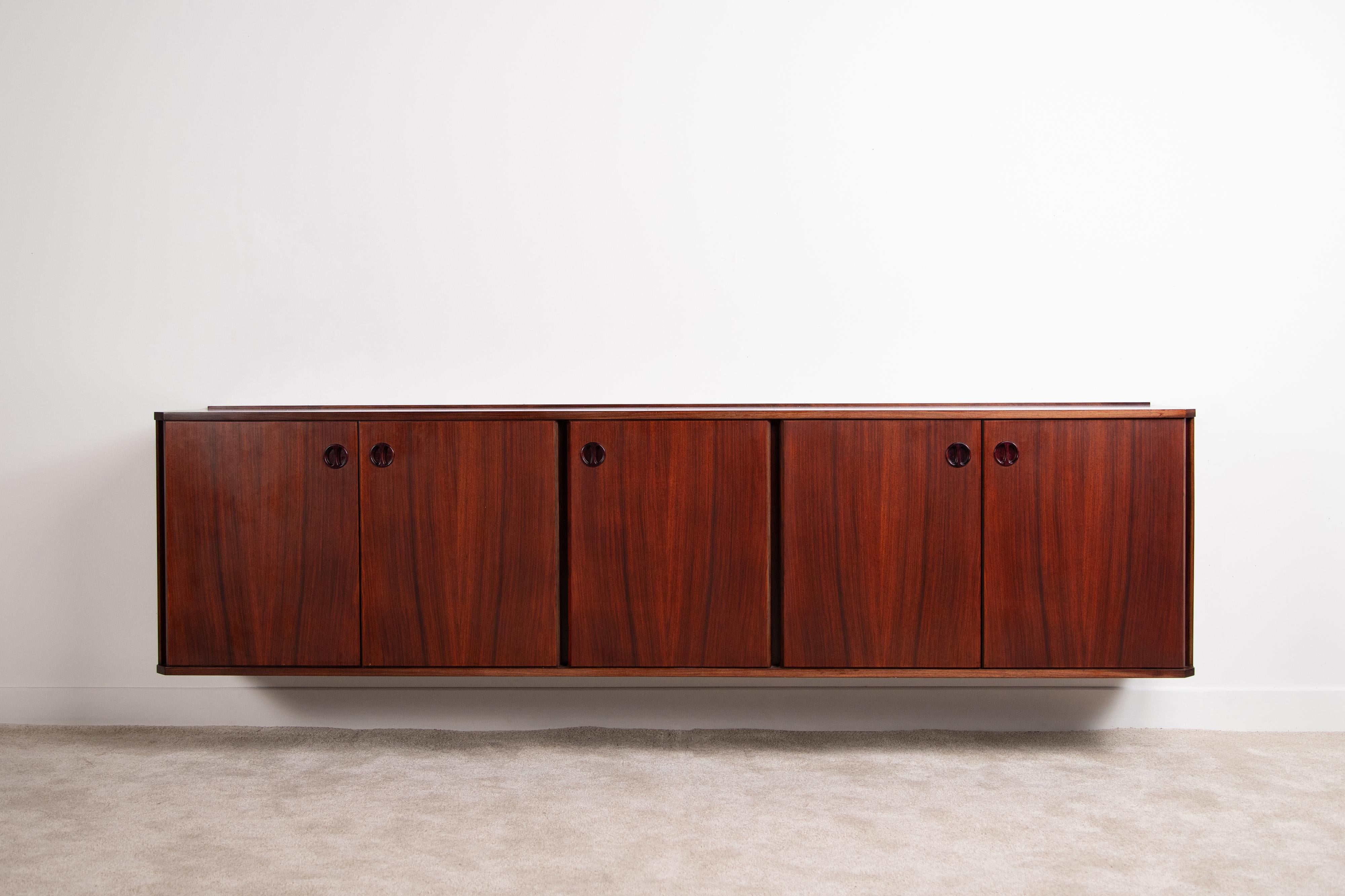 Italienisches Wand-Sideboard aus den 1960er Jahren, furniert. Das Fehlen von Füßen verleiht dem Schrank eine minimale und leichte Linie. In der mittleren Tür befinden sich fünf Schubladen mit einem eleganten Griff aus Massivholz, während in den