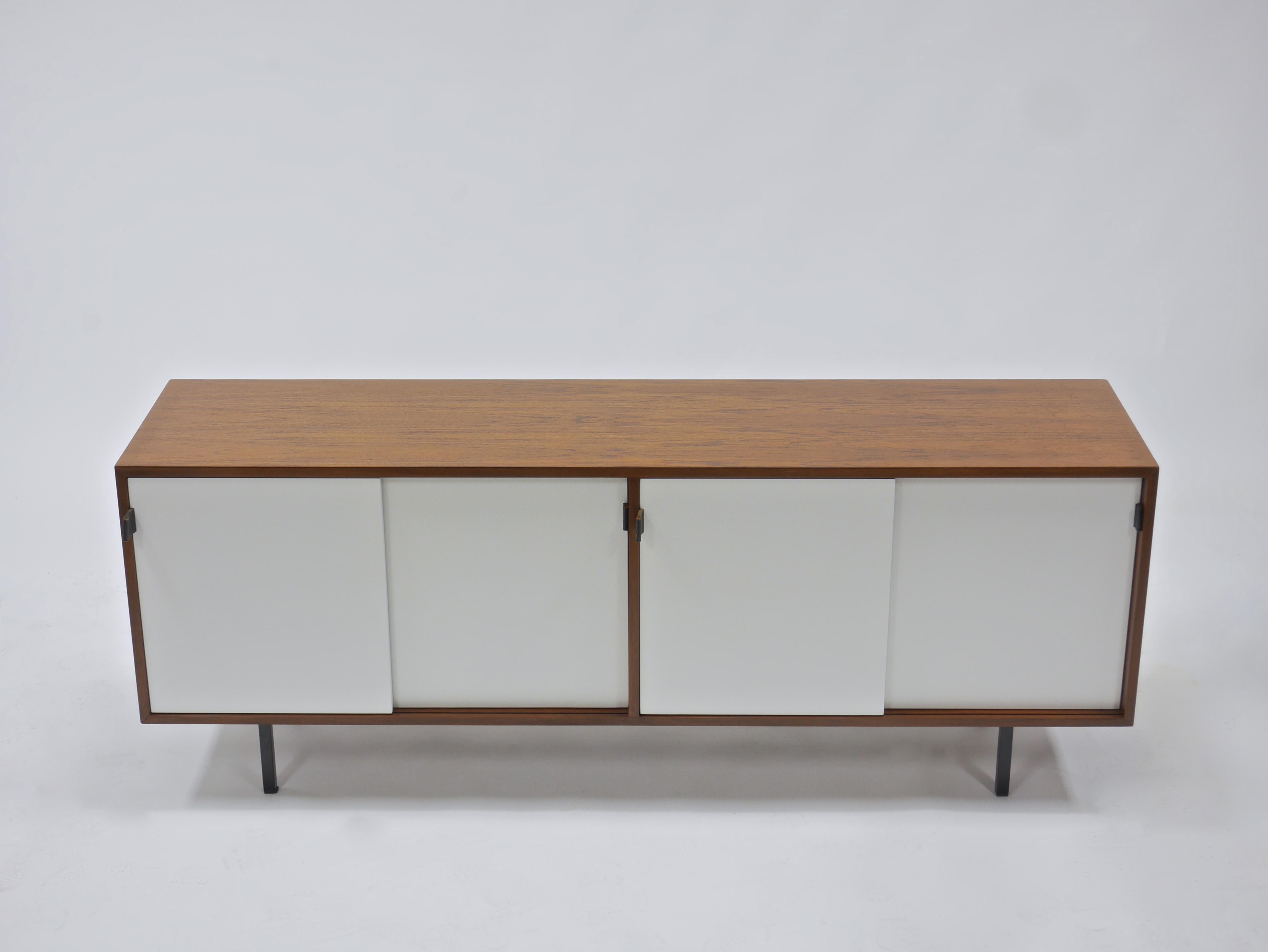 Credenza in walnut and white lacquer by Florence Knoll. Having leather pulls, steel legs and four oak lined compartments, each with a shelf. A handsome example with highly figured walnut veneers. Knoll Associates label. See our other listings for a