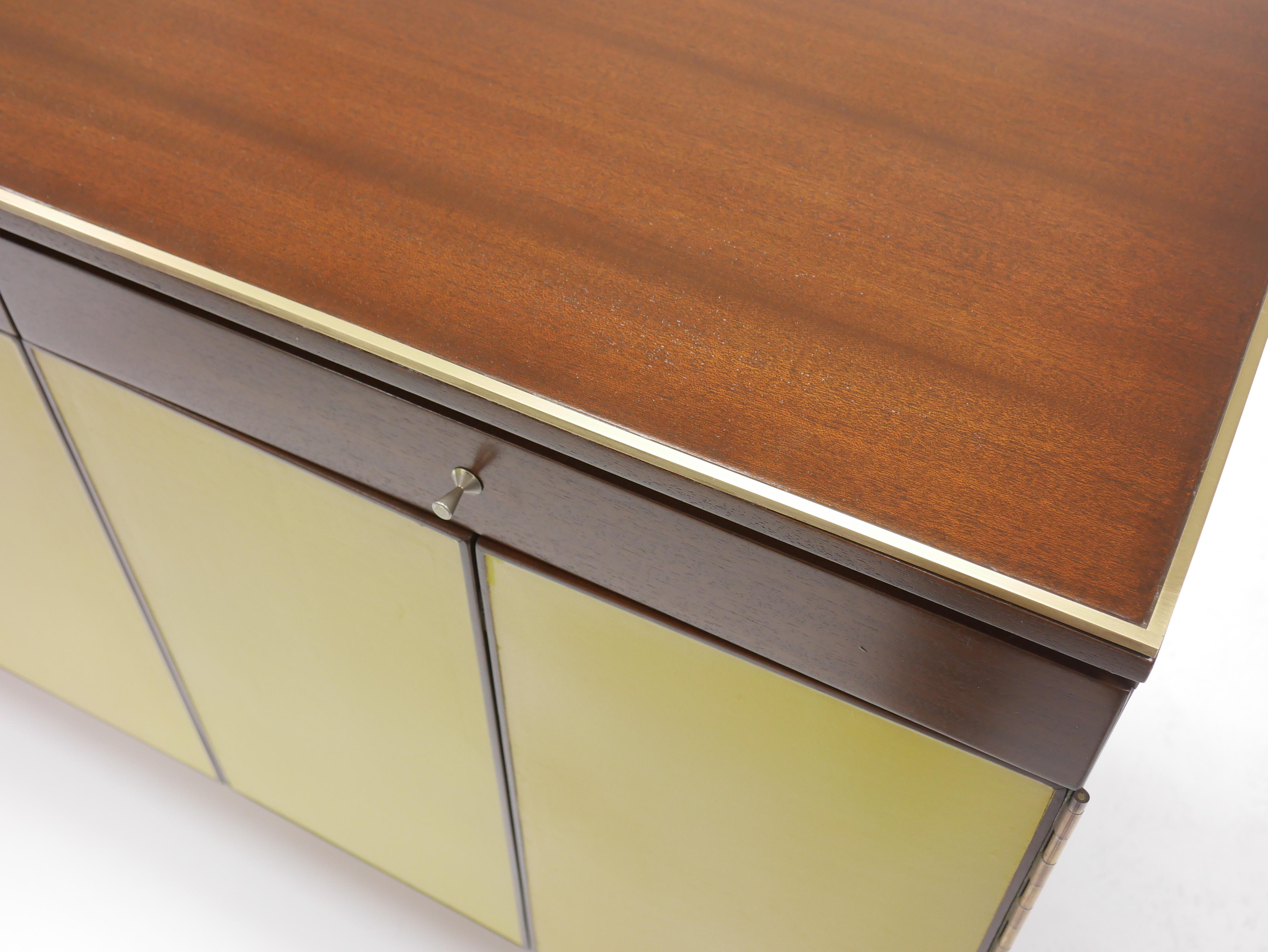 Unusual Paul McCobb for Calvin Group mahogany and leather front credenza with flat bar brass legs. Accordion trifold doors open to reveal 6 leather lined drawers.