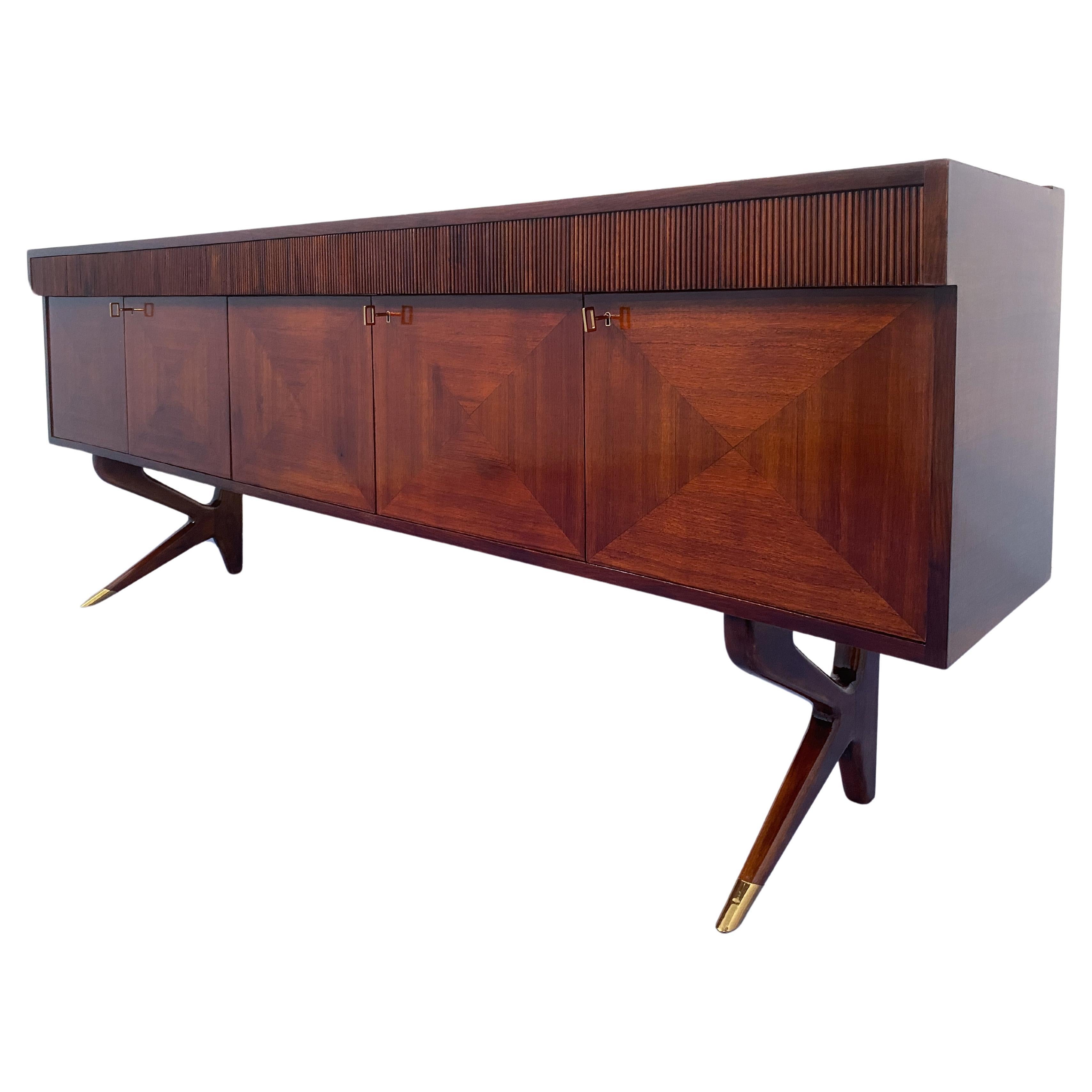 Credenza italiana dal design stiloso disegnata da Vittorio Dassi negli anni '50 e '60 del Novecento. Le cinque ante presentano raffinati disegni geometrici sul fronte, mentre la parte centrale è adibita a vano bar con ripiano in vetro. I cinque