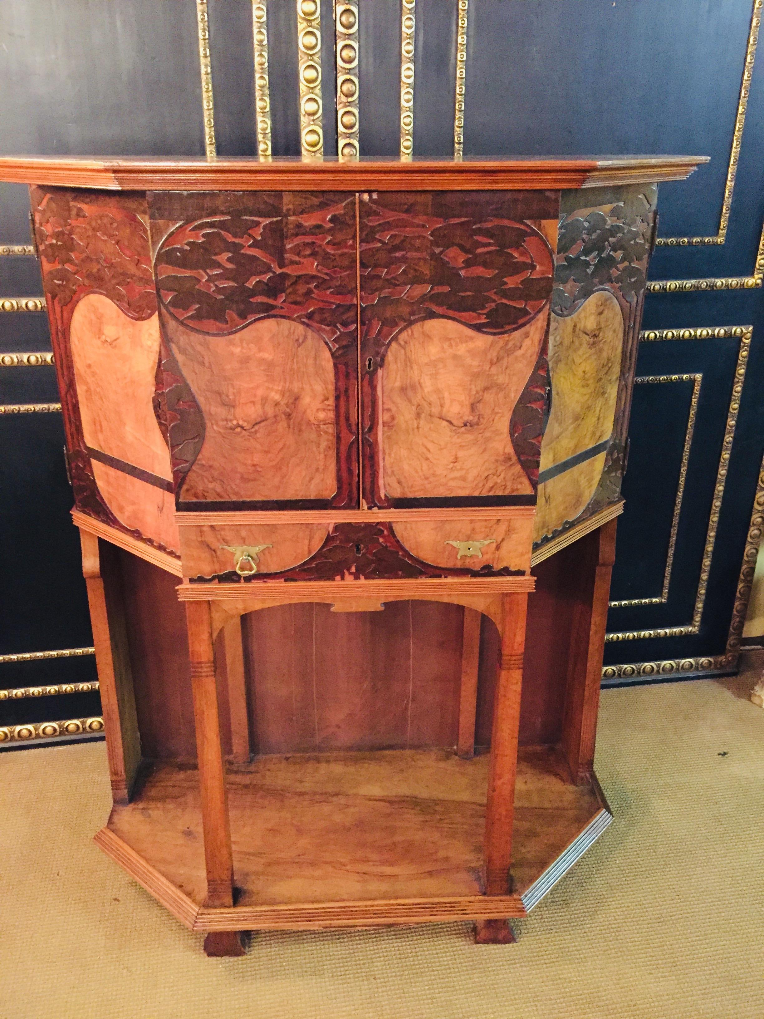A French Art Nouveau walnut credenza in ash and rosewood, featuring depicted in marquetry and deep carving. The credenza has four lockable storage areas, each with a shelf and two drawers,
circa 1900.