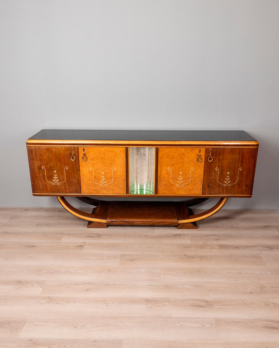 Buffet à structure en bois de bruyère et placage de noyer, poignées en laiton doré, plateau en verre noir avec décorations. Design art déco italien, années 1930.

ÉTAT : En bon état, peut présenter des signes d'usure au fil du temps.

DIMENSIONS :