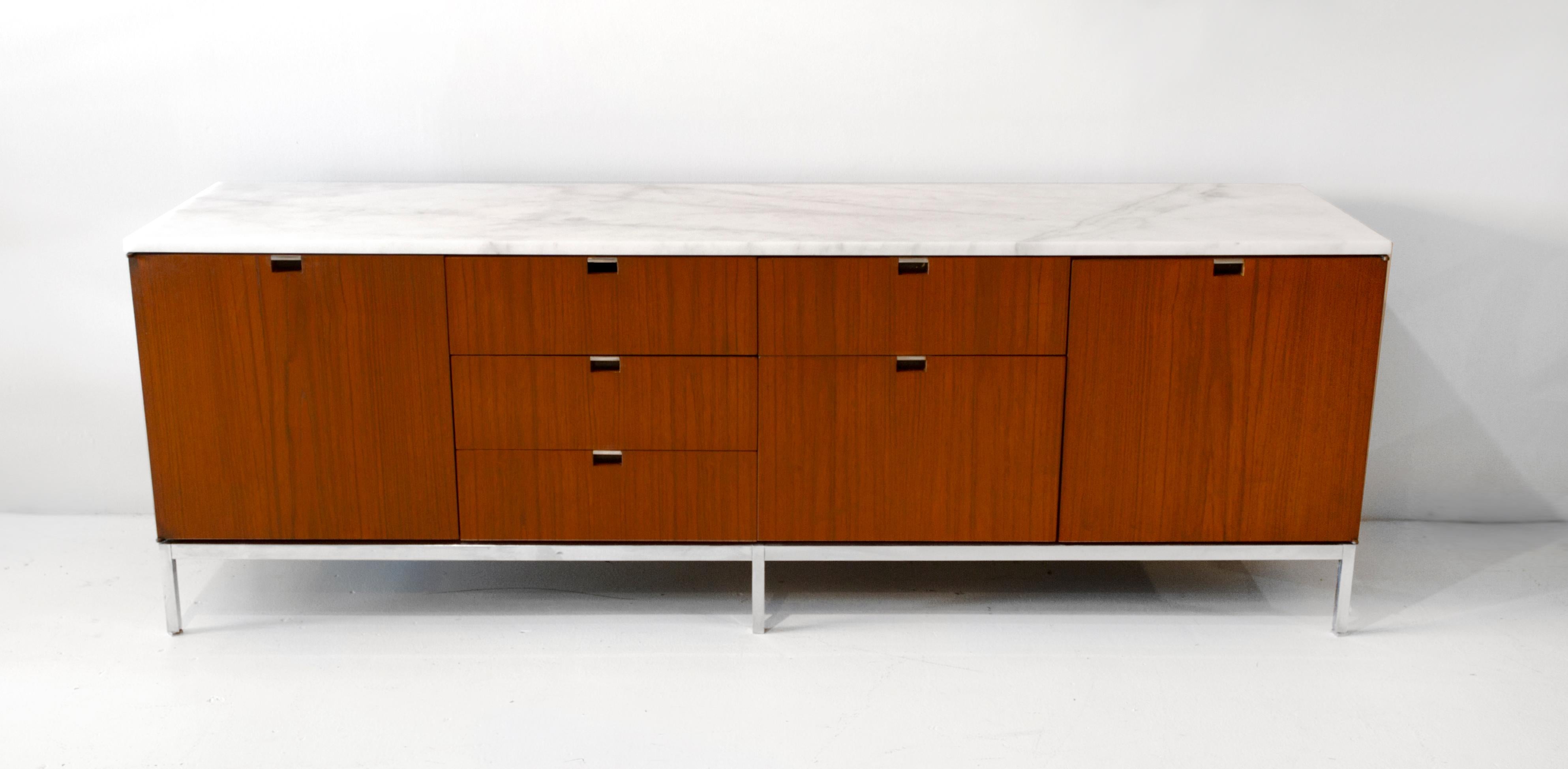 Beautiful credenza designed by Florence Knoll for Knoll International. Constructed with teak wood, marble top and oak interior, the left door opens to reveal a pull-out shelf, right door conceals adjustable shelf. The credenza is in very good