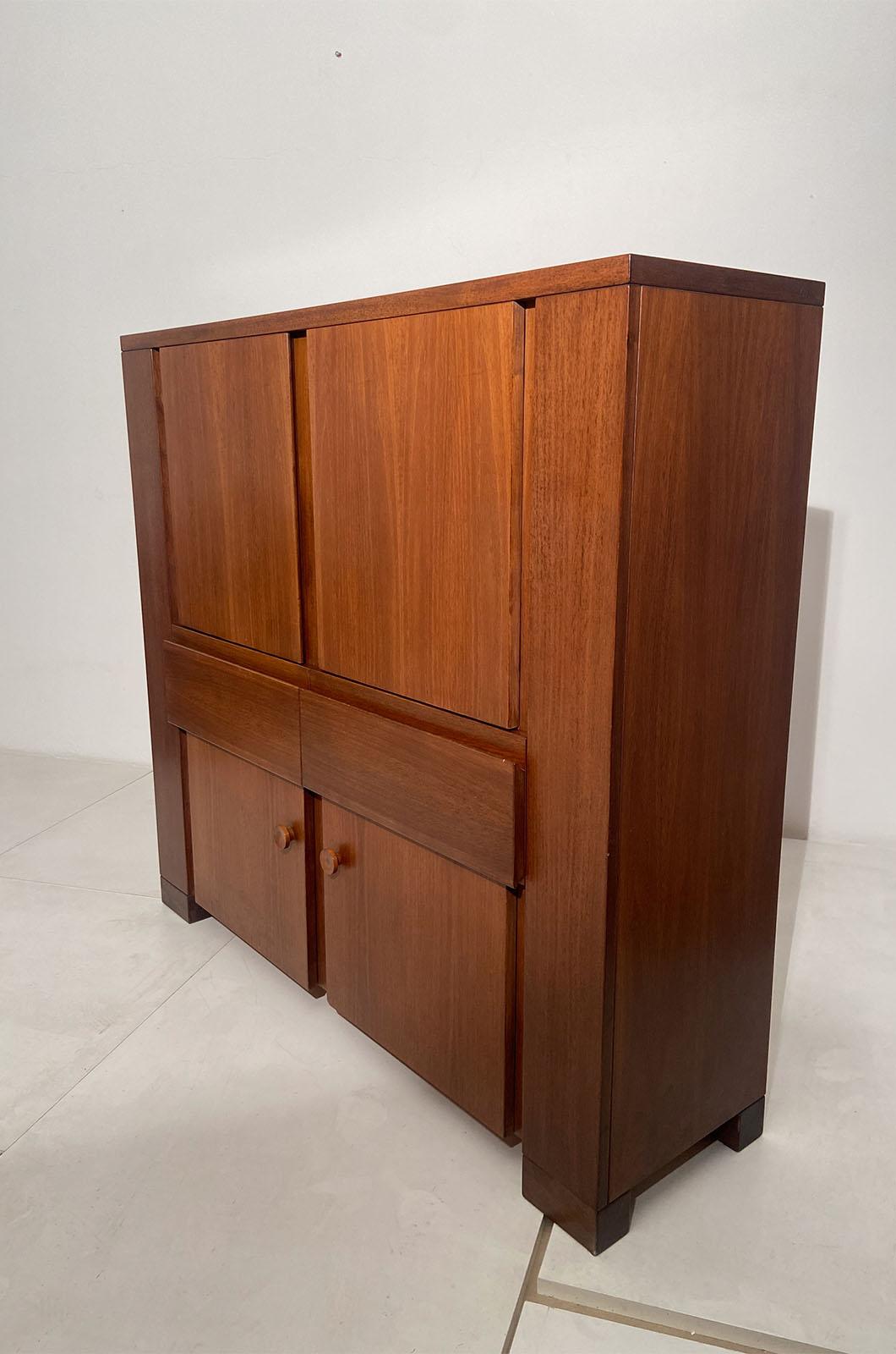 Muebles diseñados por Michelucci y fabricados por Poltronova. El armario consta de dos puertas abatibles inferiores, que se abren mediante un tirador, y dos puertas abatibles superiores, que se abren mediante una ranura central. La parte central
