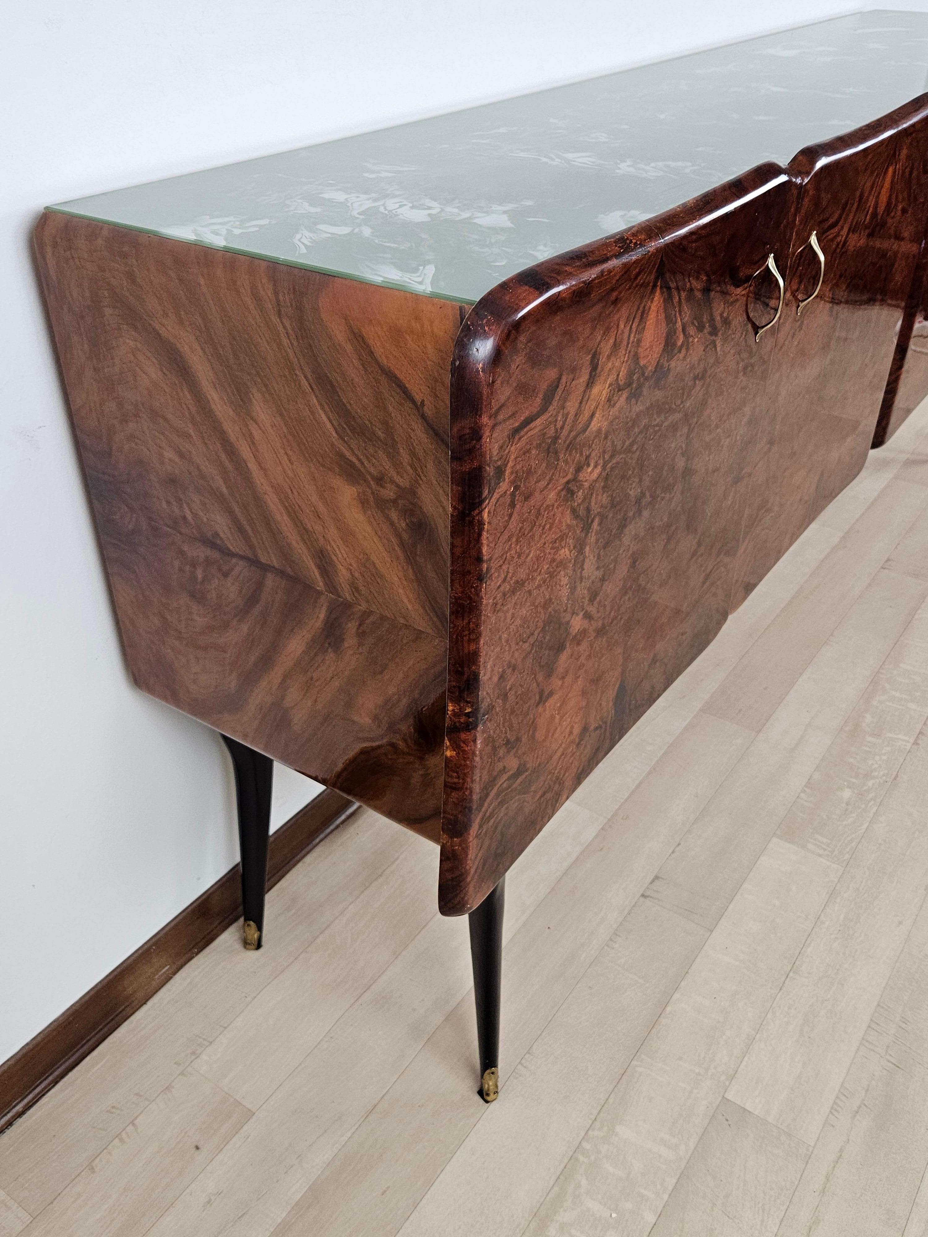 Elegant Venetian Sideboard made of Walnut Burl and Teak Feather with teal/ Tiffany colored Glass top.
Rosewood legs with Brass escutcheons and decorations on the sides are synonymous with elegance and refinement.
Glass in perfect condition.
Shellac