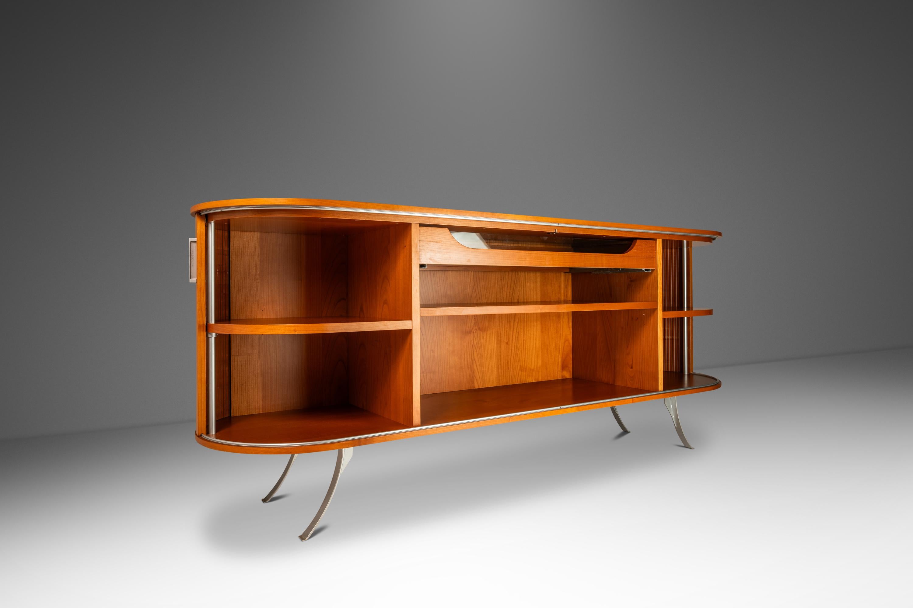 Te presentamos un aparador único fabricado en Italia por los renombrados fabricantes de muebles Fattori Studios. Fabricado en madera de cerezo y con un diseño de doble puerta de persiana envolvente sobre patas metálicas en voladizo, este aparador es