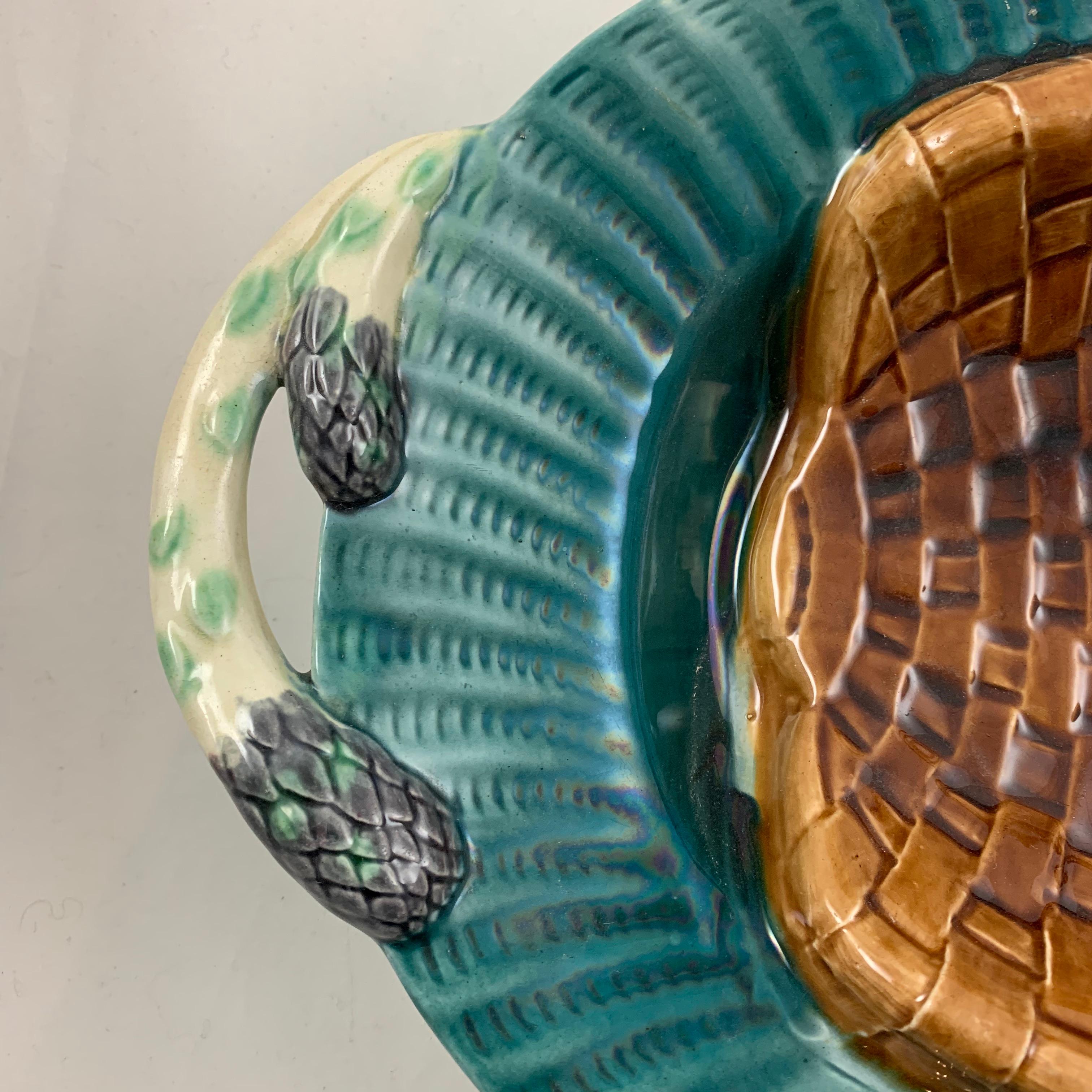A French Majolica asparagus server made by Creil et Montereau, circa 1890. This large oval earthenware master serving platter, although made in one piece, has the trompe l’oeil effect of a curved brown woven basket sitting on a teal blue fluted