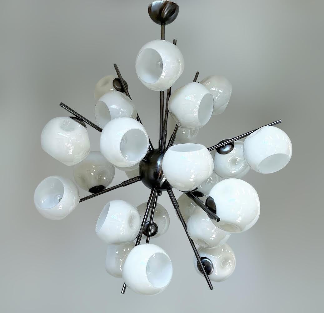 Lampadario Sputnik Modern italiano con paralumi in vetro di Murano color crema montati su una struttura in metallo con finitura in nichel nero satinato / Made in Italy
24 luci / tipo E12 o E14 / max 40W ciascuna
Misure: Diametro 34 pollici / Altezza