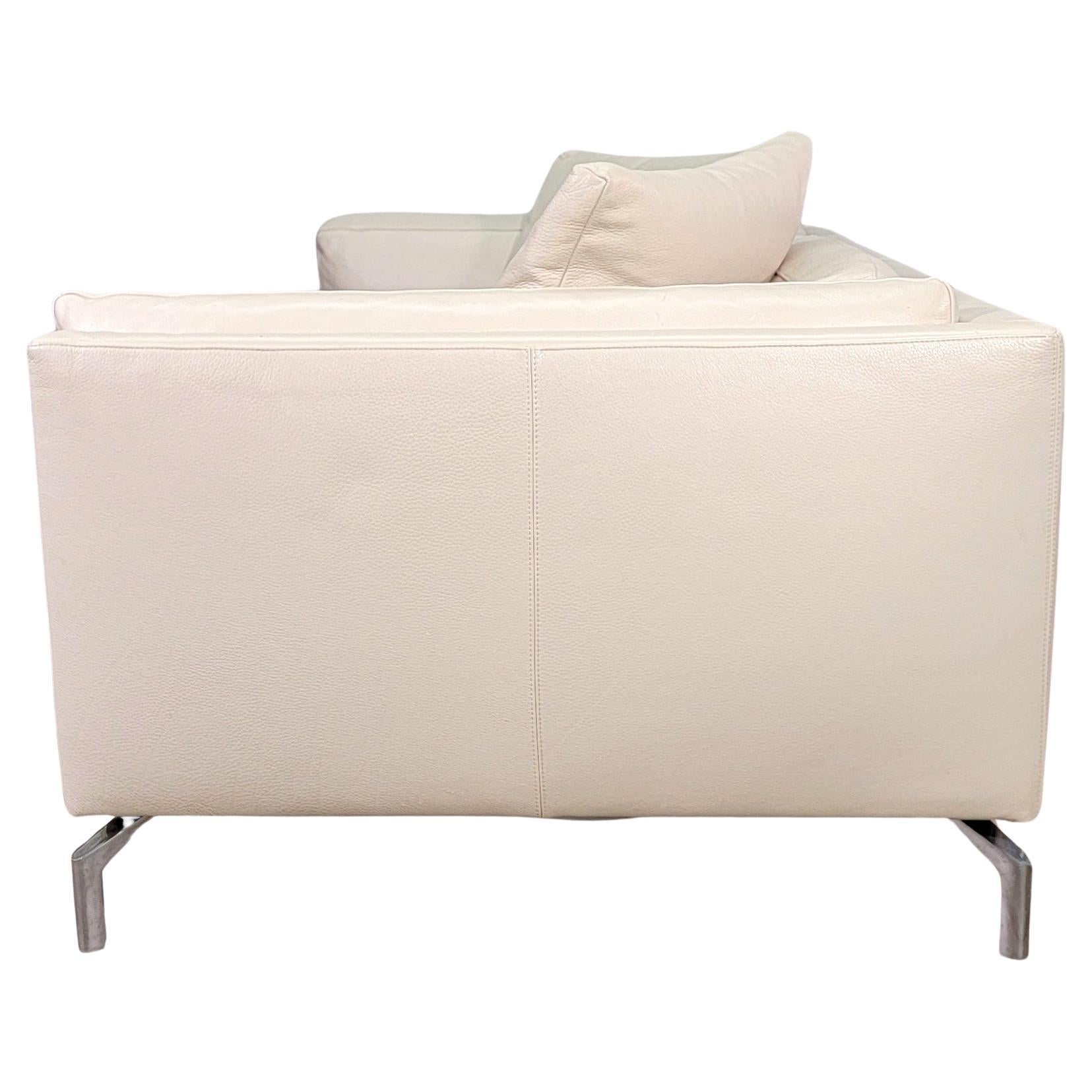 Divano in pelle bianco sporco avorio disegnato da Giorgio Soressi per Design Within Reach (aka DWR). Elegante e confortevole, questo divano color crema è costruito con una solida struttura in acciaio, gambe in alluminio fuso lucidate e