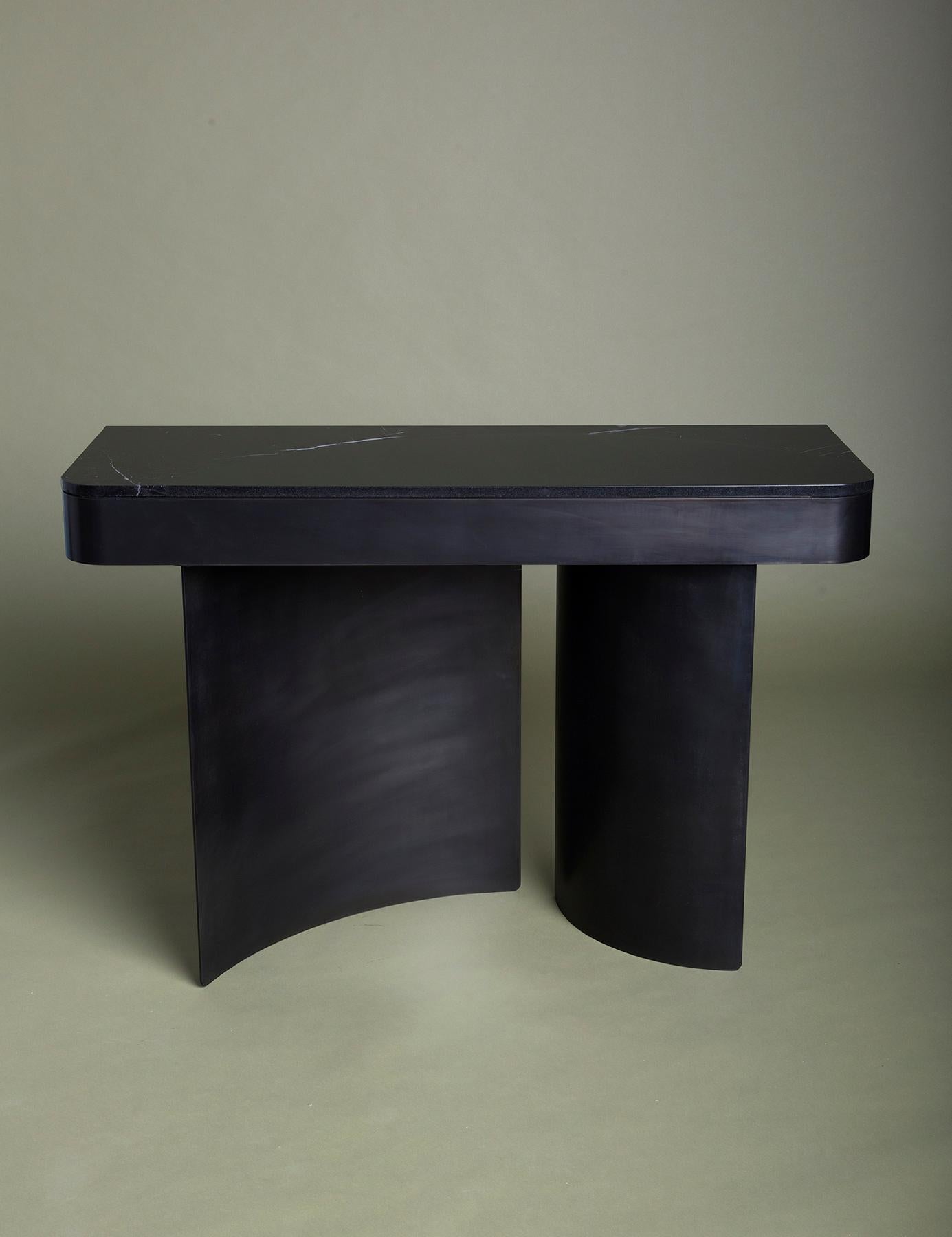 Primary circles are broken into sinuous steel arcs to form the base of the crescent console. They are then transcribed to the surface, leaving a sweeping line that separates the stone slabs. The subtle color and texture variations of the all-black