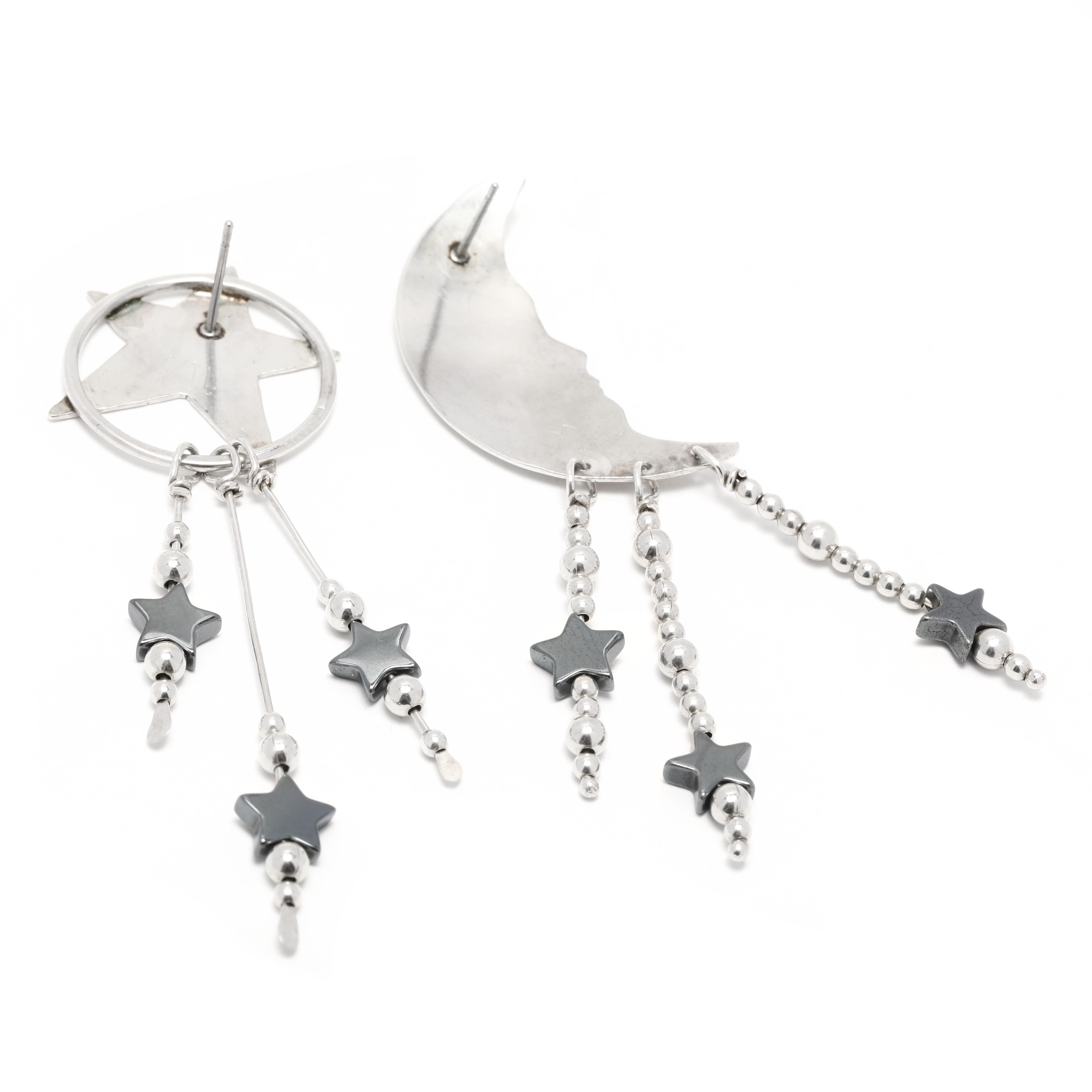 These Crescent Moon and Stars Hematite Large Dangle Sterling Silver Earrings make a stunning statement! Crafted from sterling silver and hematite, these earrings feature a crescent moon and five stars dangle from a hoop. With a length of 2.75