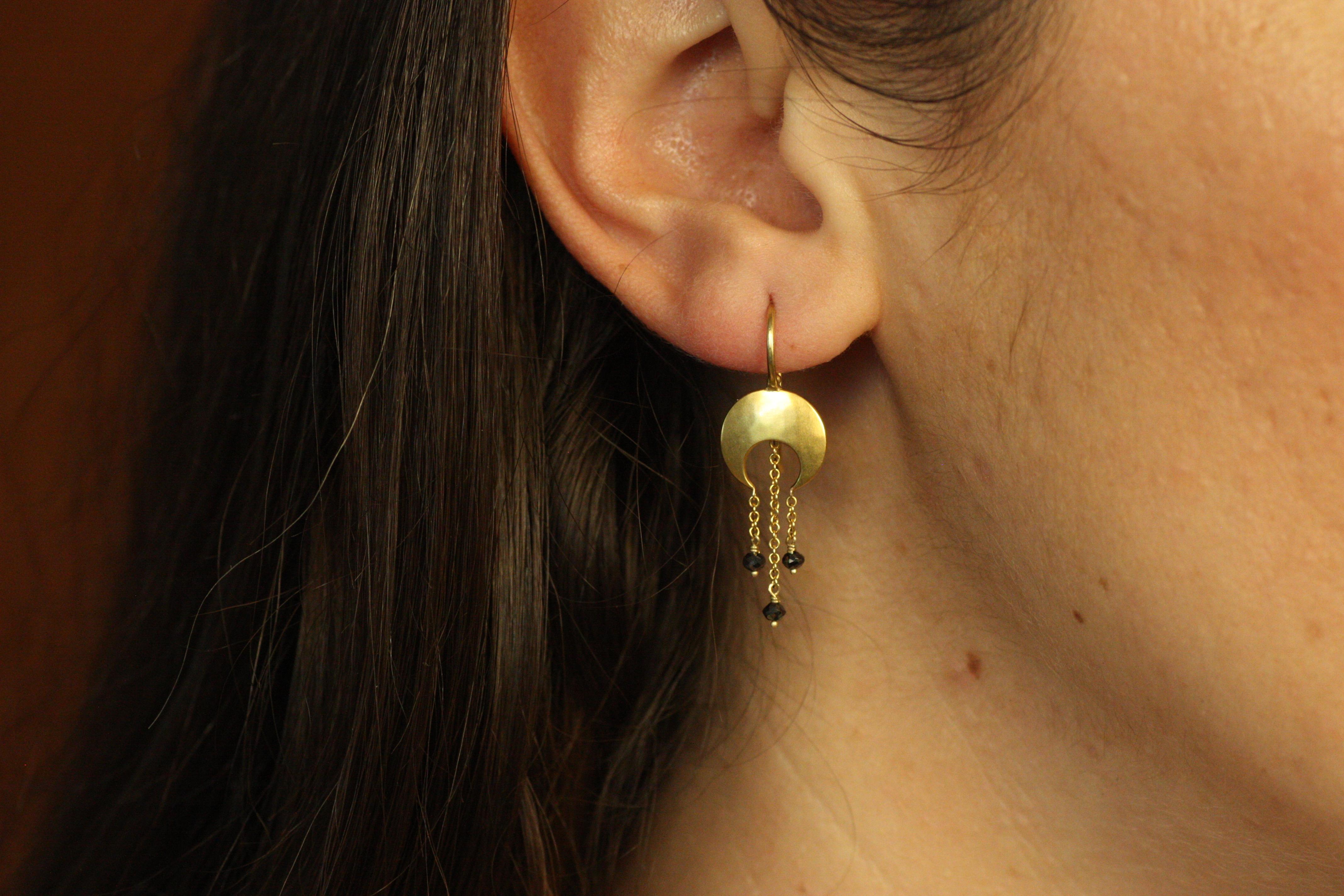 Inspired by the beauty of celestial events, these Eclipse Earrings feature 22K yellow gold moon discs with hanging black diamond accents. The earrings' bold, modern design is perfect for those who love to make a statement, while the craftsmanship