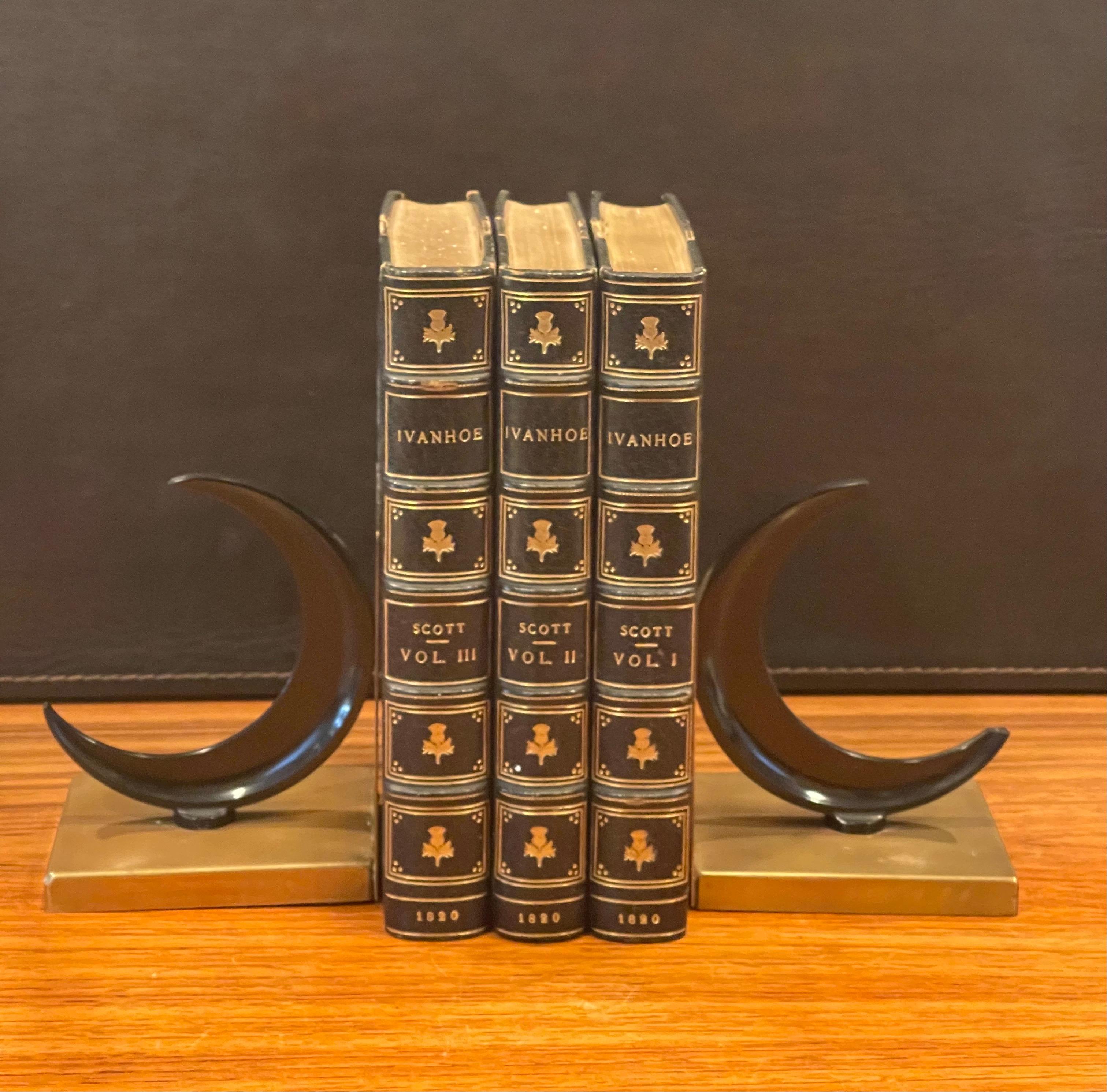Gorgeous pair of bakelite crescent moon and brass Art Deco bookends by Walter Von Nessen for Chase & Co., circa 1930s. The bookends have a black bakelite crescent moon siitting on a brass 