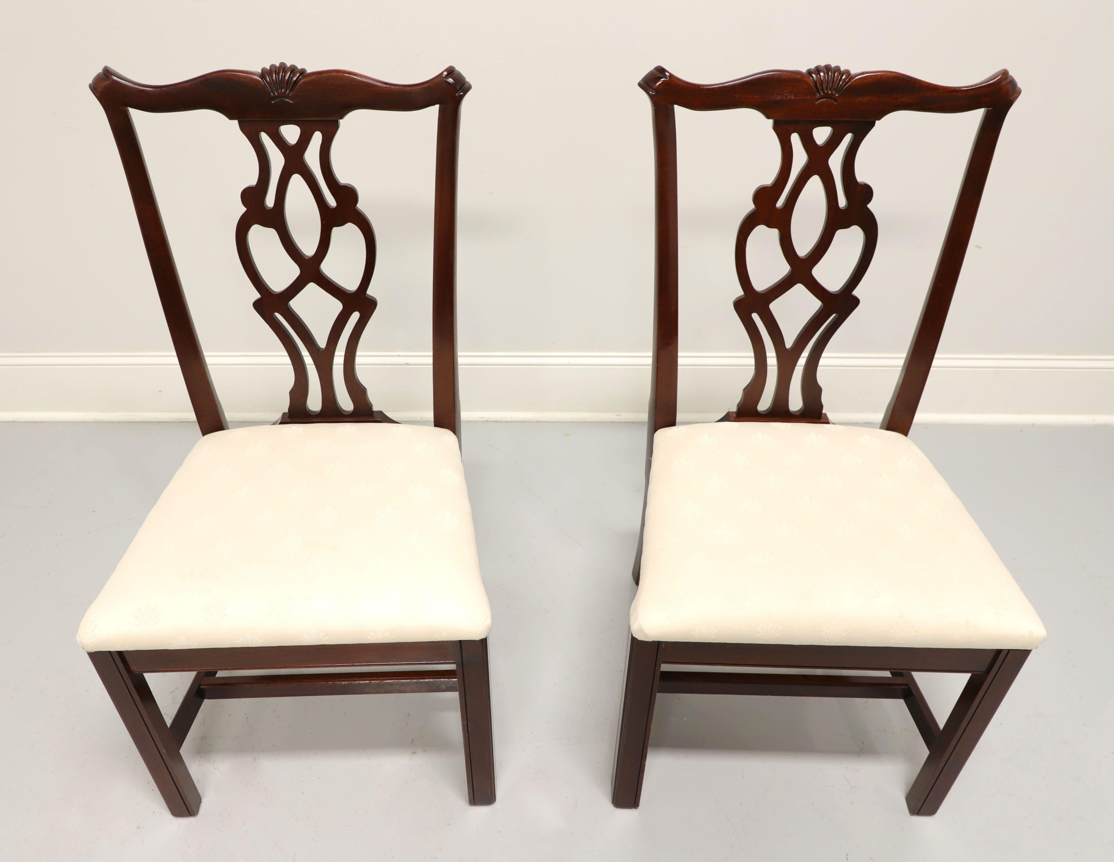 A pair of dining side chairs in the Chippendale style by Cresent, of Gallatin, Tennessee, USA. Mahogany, with fan carving to crestrail, carved backsplat, neutral cream colored brocade fabric upholstered seat, straight legs and stretcher base. Made