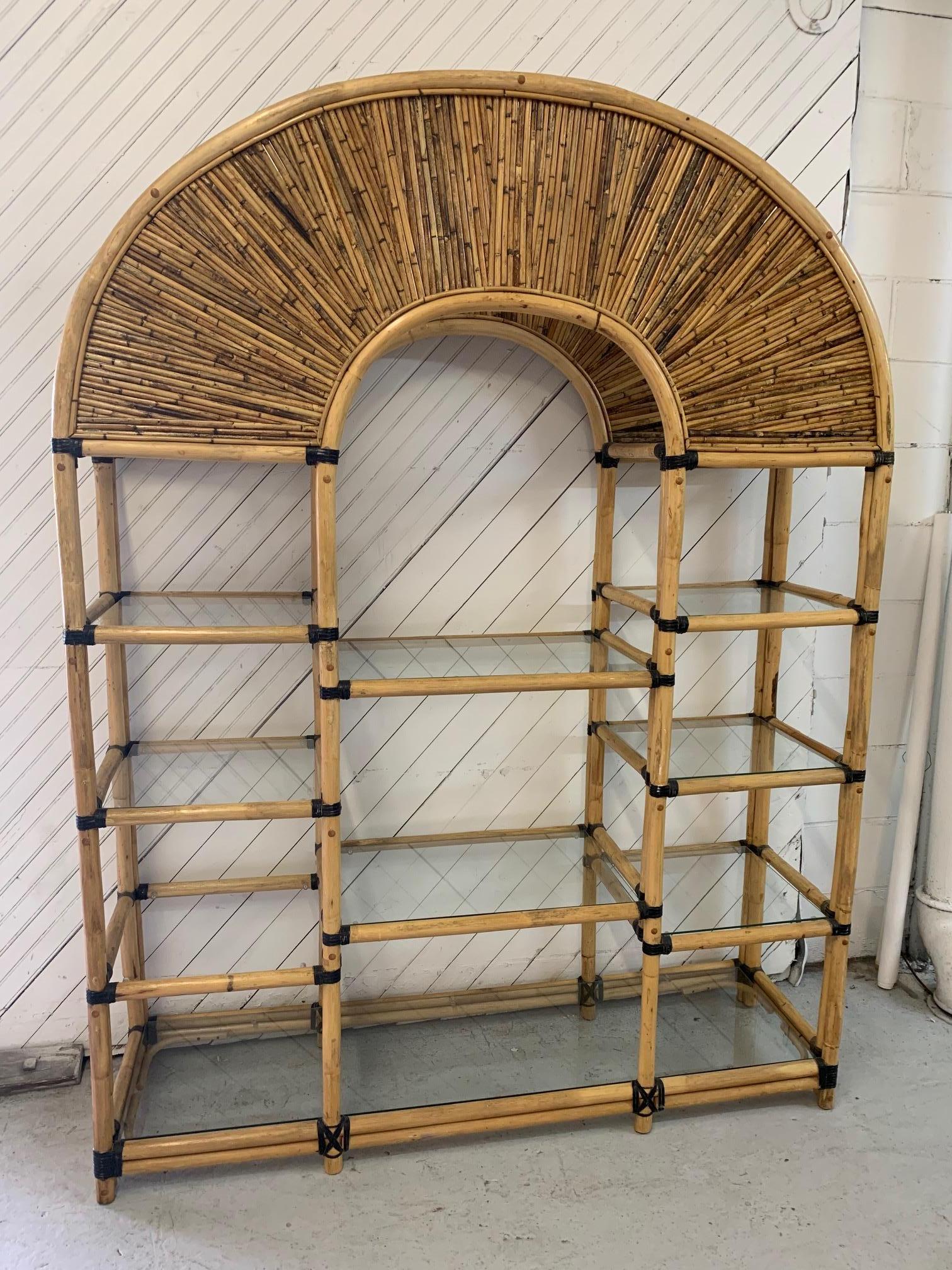 Large rattan étagère features inlay across arched top and glass shelving for storage and display. Very good vintage condition with minor imperfections consistent with age.