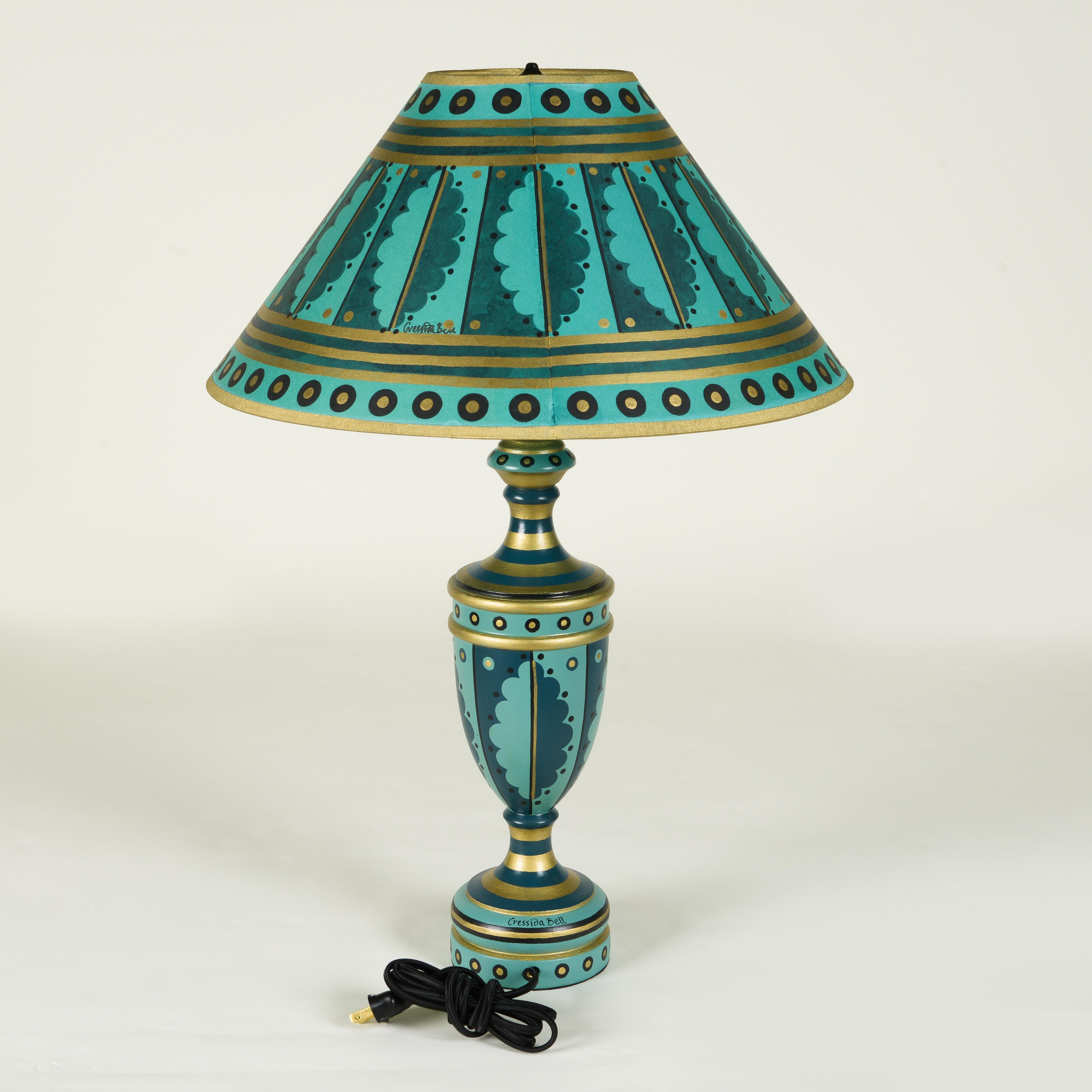 Handbemalte Tischlampe mit Holzsockel und passendem Schirm, verziert mit verschiedenen Blau-, Gold- und Schwarztönen.

Cressida Bell ist eine britische Designerin, die sich auf Textilien und Inneneinrichtungen spezialisiert hat. In ihrem Londoner