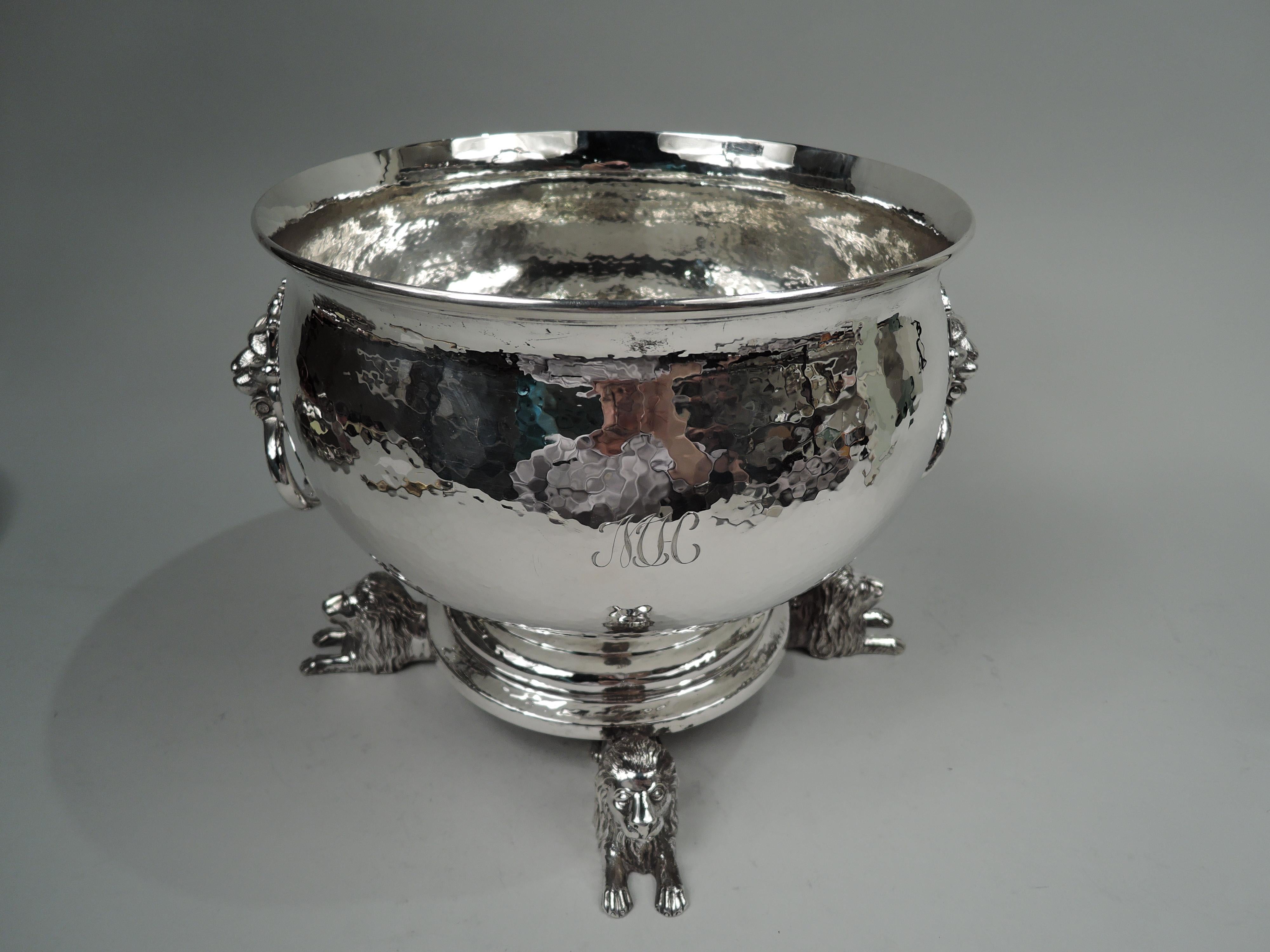 George V sterling silver bowl. Made by Lionel Alfred Crichton in London in 1912. Curved with flared rim and stepped foot. Cast lion’s head side mounts in leafing-scrolled frames with loose-mounted rings. Four cast lion couchant supports with