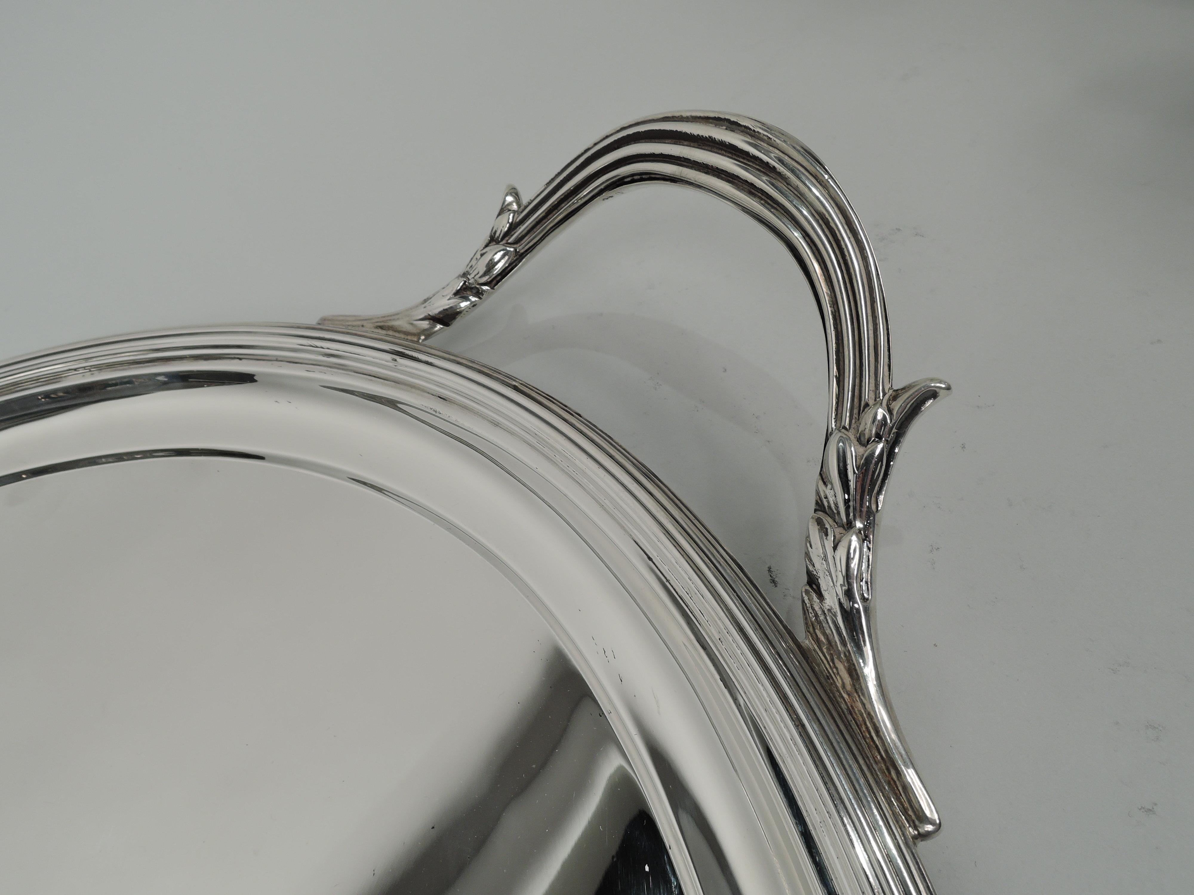 George V sterling silver tea tray. Made by Lionel Alfred Crichton in London in 1922. Oval well with reeded rim and leaf-capped c-scroll end handles. Classicism that works with traditional and Modern services. Fully marked. 

Overall dimensions: H