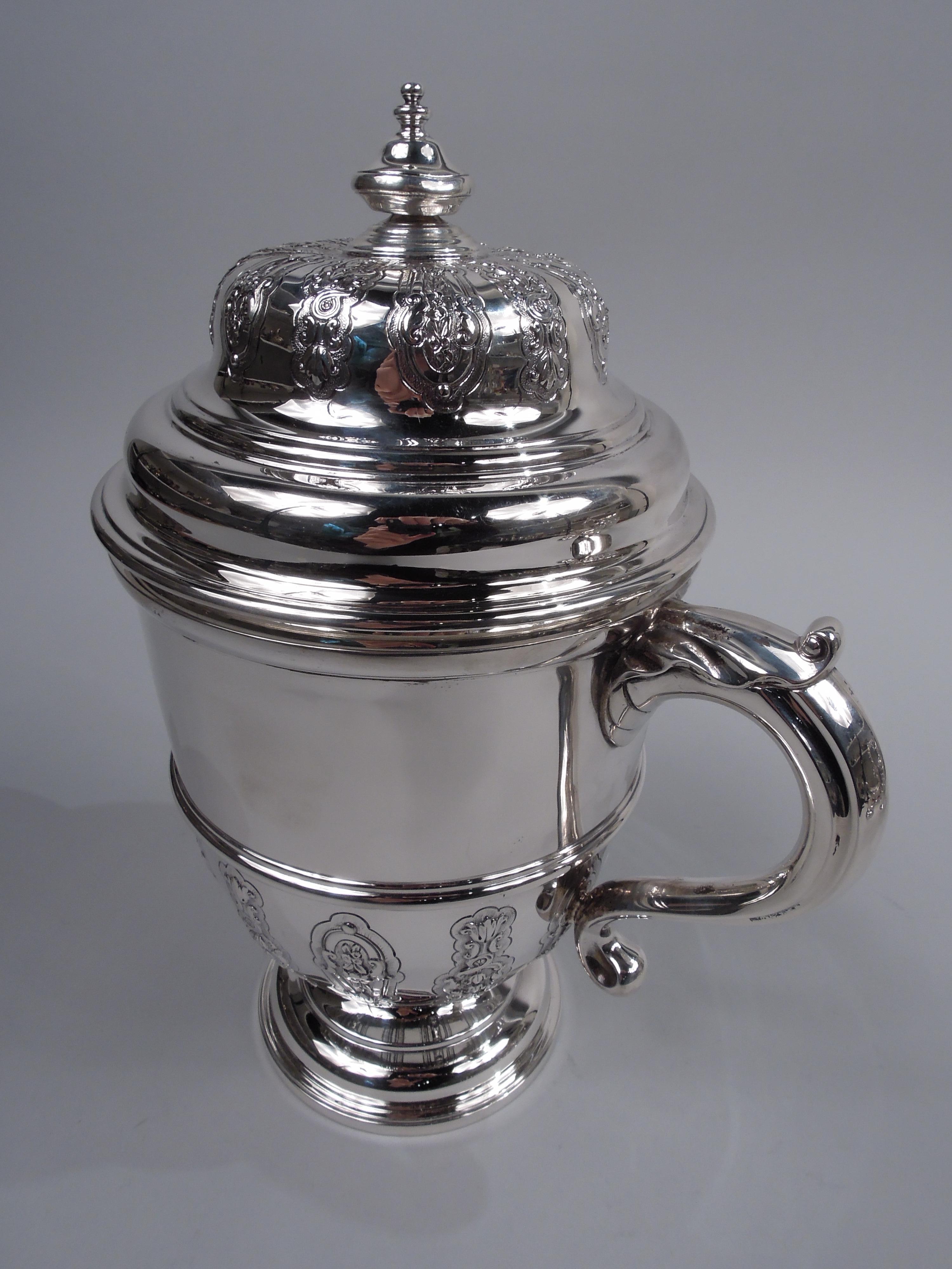 George V sterling silver covered urn. Made by Lionel Alfred Chrichton in London in 1916. Girdled urn with half strapwork on stepped domed foot; leaf-capped s-scroll sides handles. Cover double domed with vasiform finial and radiating strapwork.