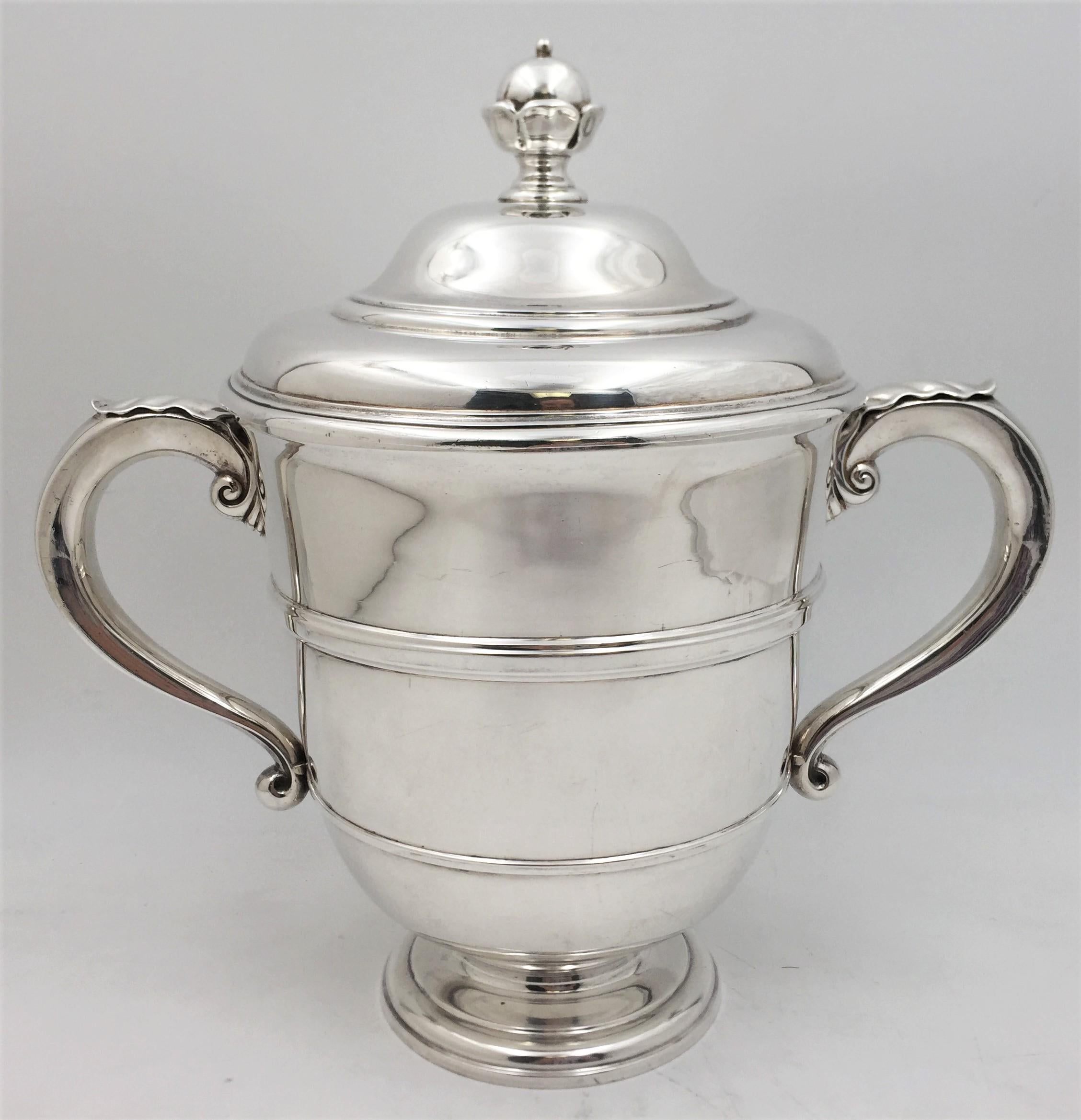 Crichton & Co., English silver two-handled trophy or urn from 1917 in exquisite Georgian style with elegant proportions. The handles have an applied leaf design, adding to the grace of the design. The body has a beautifully engraved monogram and two