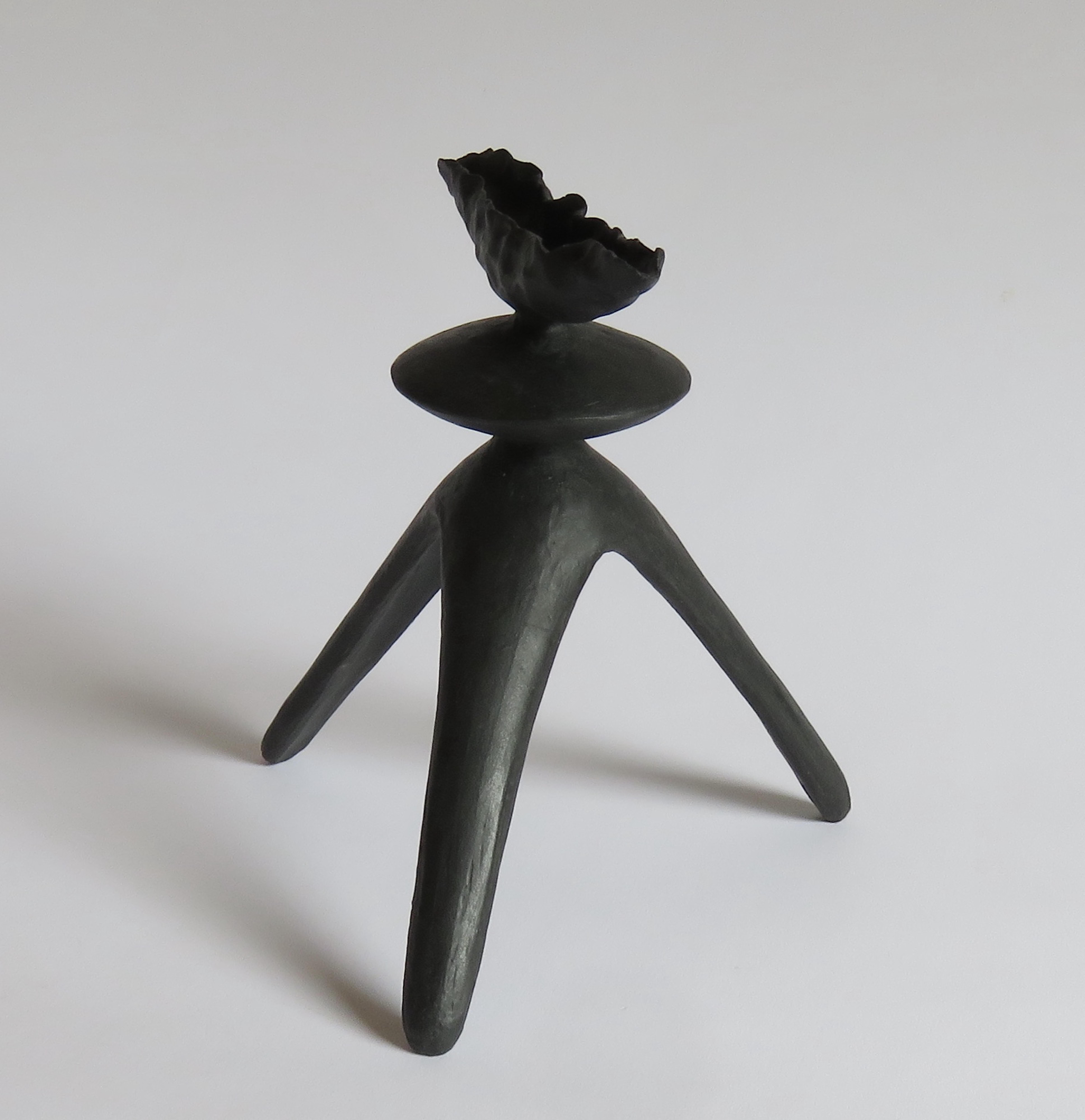 This matte black hand built ceramic TOTEM consists of a uniquely crimped top with a middle sphere on tripod legs. Part of a series of Modern Primitive Works. The dark brown stoneware clay is coated in a black underglaze to show all the hand markings