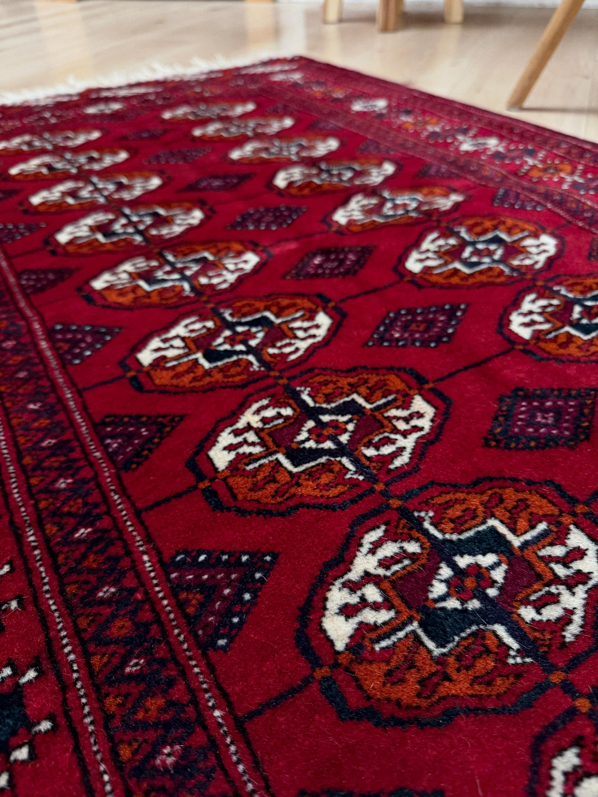 Questo tappeto Bukhara, annodato a mano e proveniente dal Turkmenistan, incarna un'arte tribale senza tempo in un formato piccolo ma potente. Caratterizzato dal classico motivo Tekke gul, mostra un allineamento ritmico di medaglioni ottagonali su un