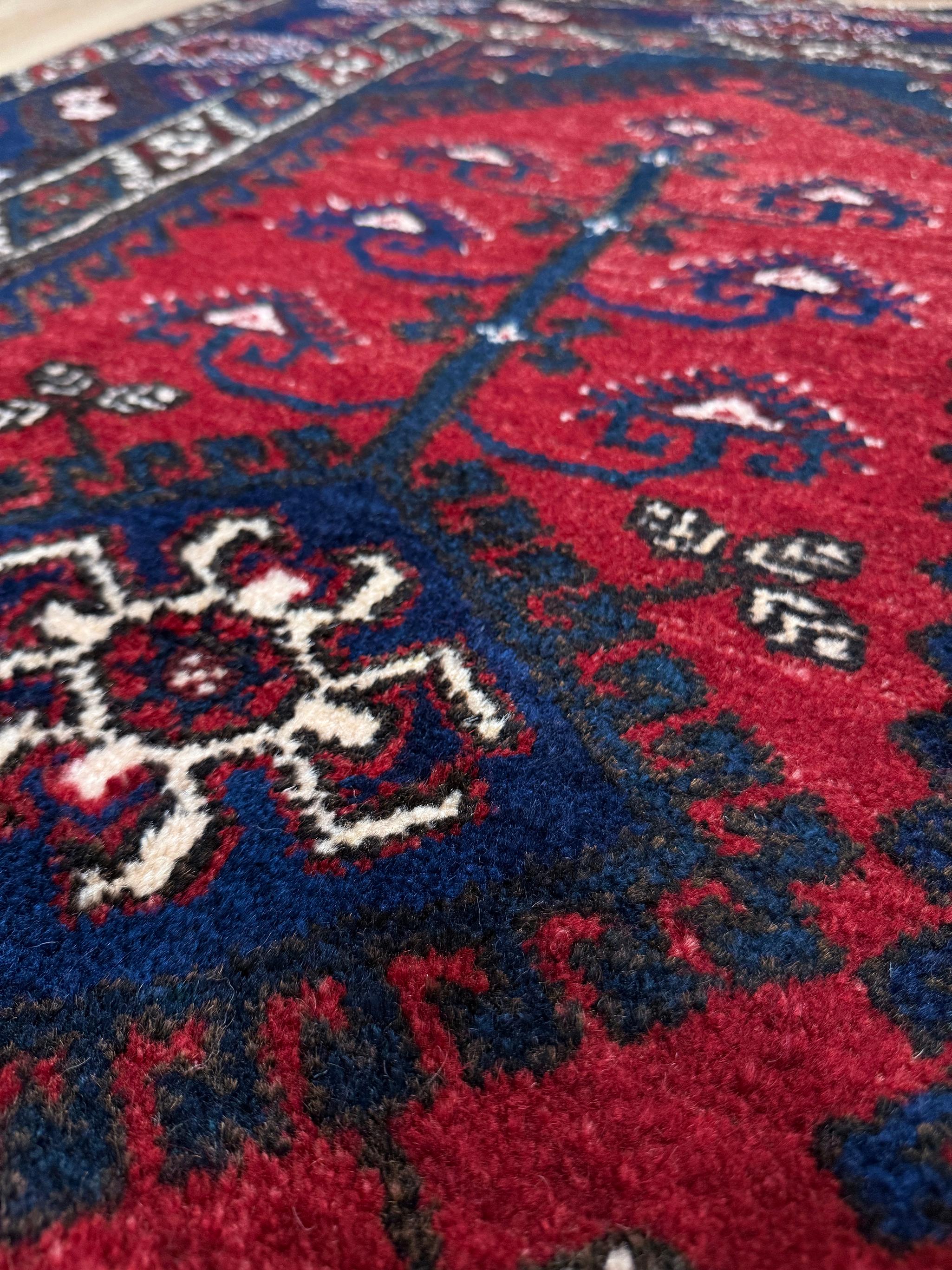 This vintage Turkish Rug  is a bold yet timeless piece woven with story, symbolism, and warmth. A deep crimson field anchors the design, while an elongated hexagonal medallion blooms with stylized floral motifs that feel both ancient and alive.