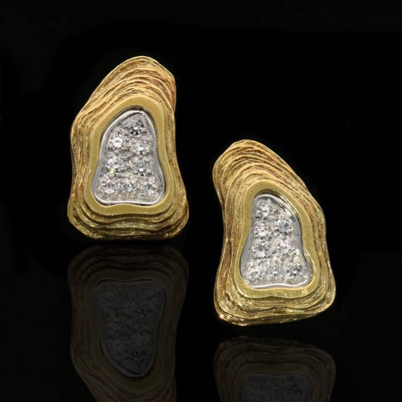 A striking pair of gold and diamond abstract earrings by Crinnan 1975, each designed as an irregular triangular disc of textured and stepped rows of 18 carat yellow gold wrapped around a central recessed free form area of single-cut diamonds pavé