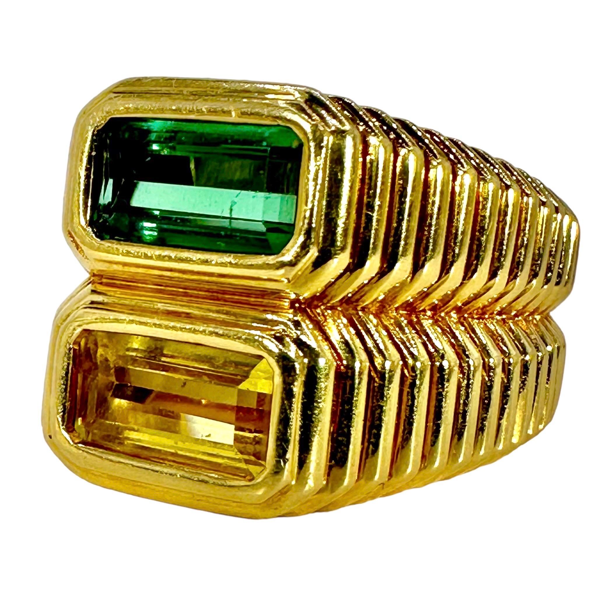 This crisp, 18K fluted yellow gold ring has one bezel set green tourmaline and one bezel set golden tourmaline stacked in the center. The style is reminiscent of rings done by one of the noted Italian design houses. The combined total weight of the