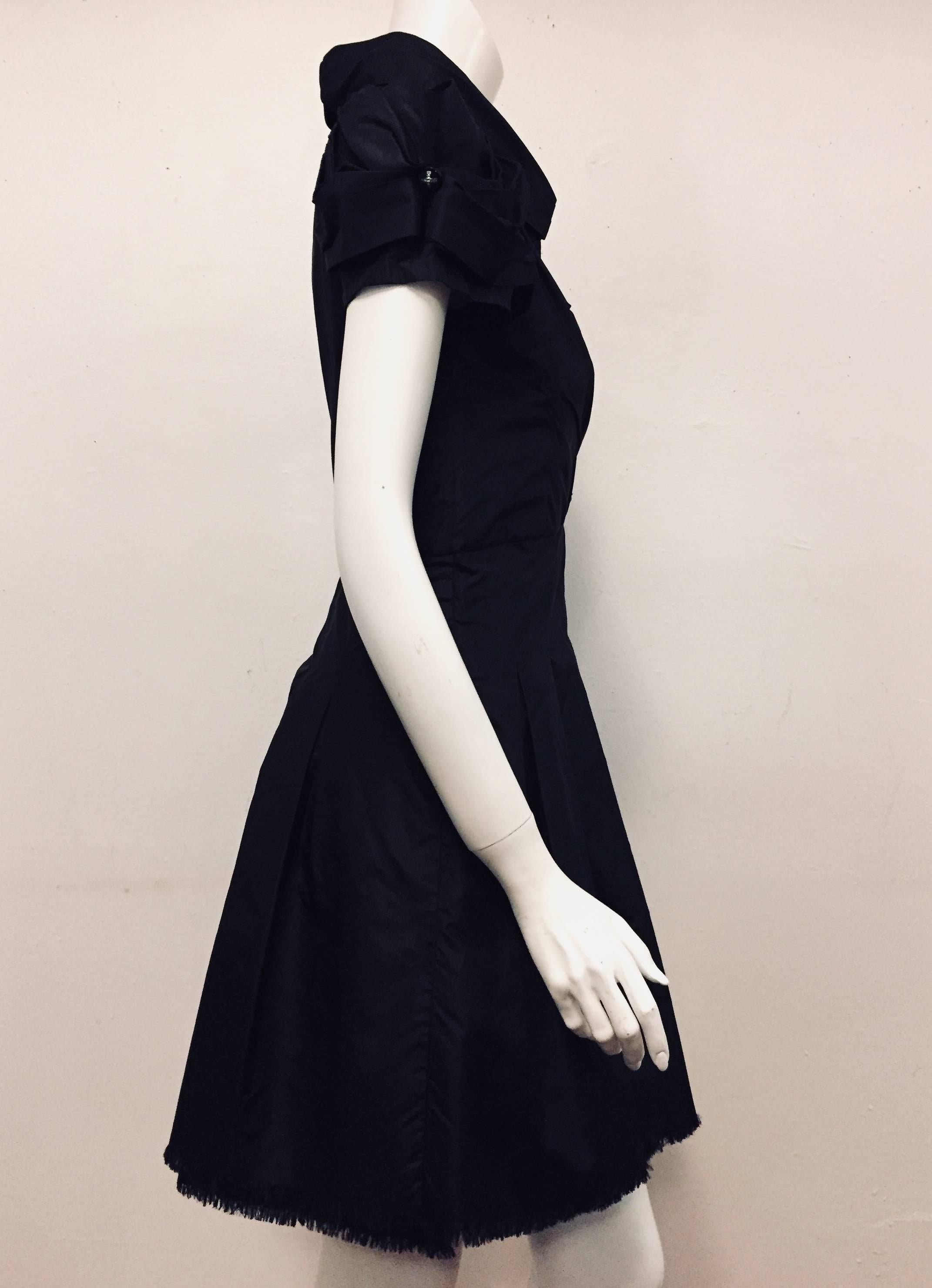 Chanel black silk dress with ruched sleeves and top is a grand addition to your Chanel collection.  The short sleeves are lined and the top tier is ruched and tied with a Chanel rhinestone X button.   The dress has up collar and the front of the
