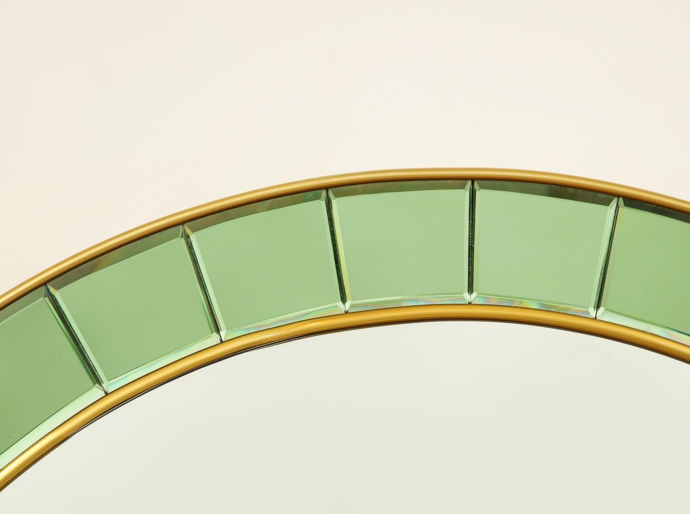 Brass, mirror, green glass tiles. Elegant wall mirror with soft-green glass tiles surrounding a central circular mirror, & brass trim.
