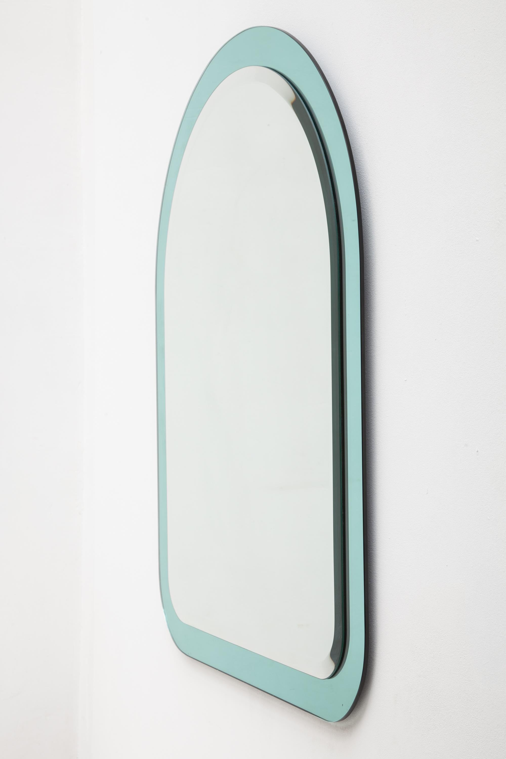Vintage 1970s mirror designed by Cristal Art in a sleek arch shape features a clear glass mirror mounted on a frame of aqua blue mirrored glass.
Mint condition.