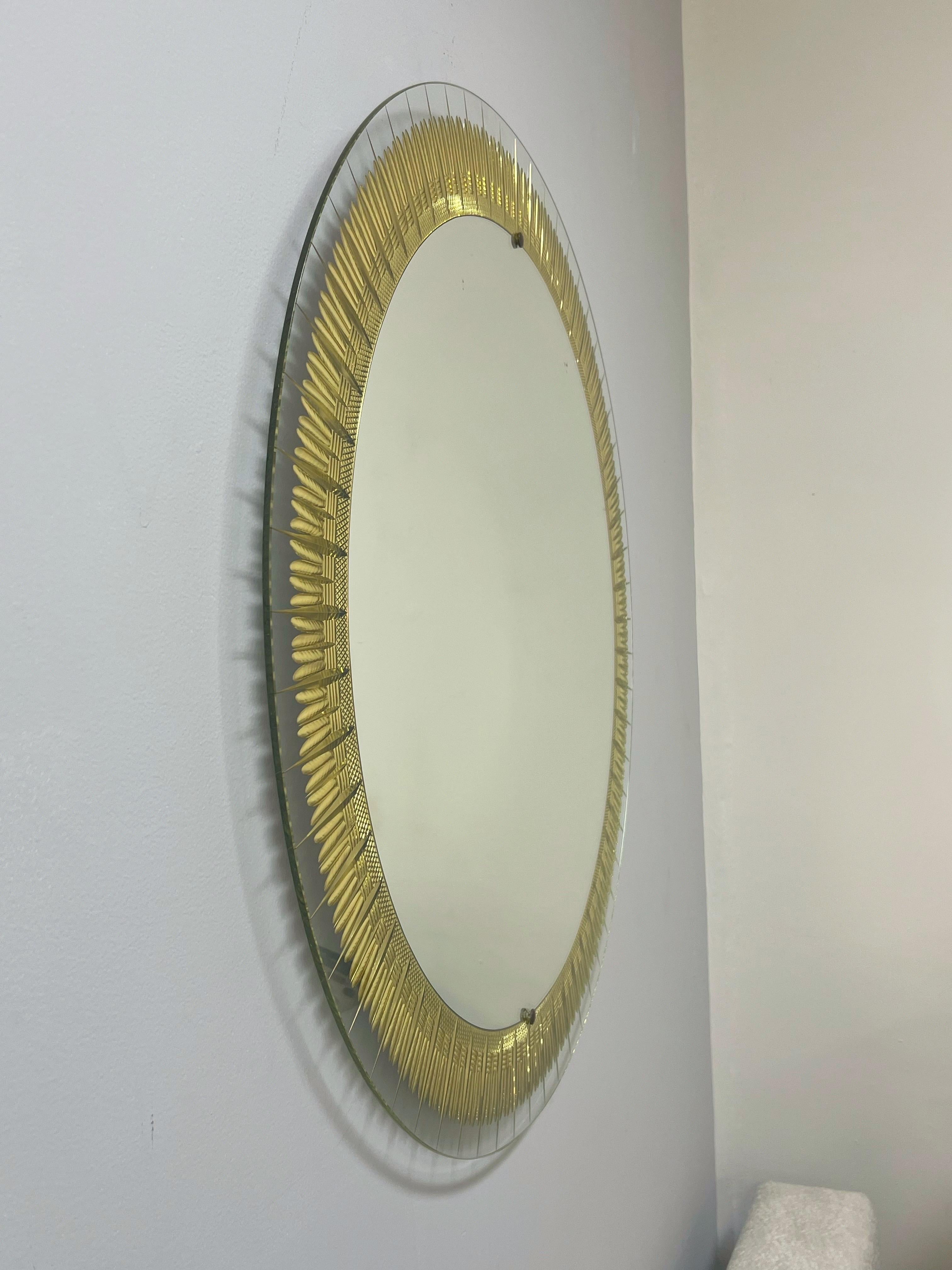 Specchio rotondo in Cristal Arte con un minuzioso motivo di piume incise a ruota e dorate, delimitato da un vetro trasparente. 
Numero di modello 2668.
Documentato in Cristal Arte La Lavorazione Artistica Del Cristallo A Torino di David Alaimo,