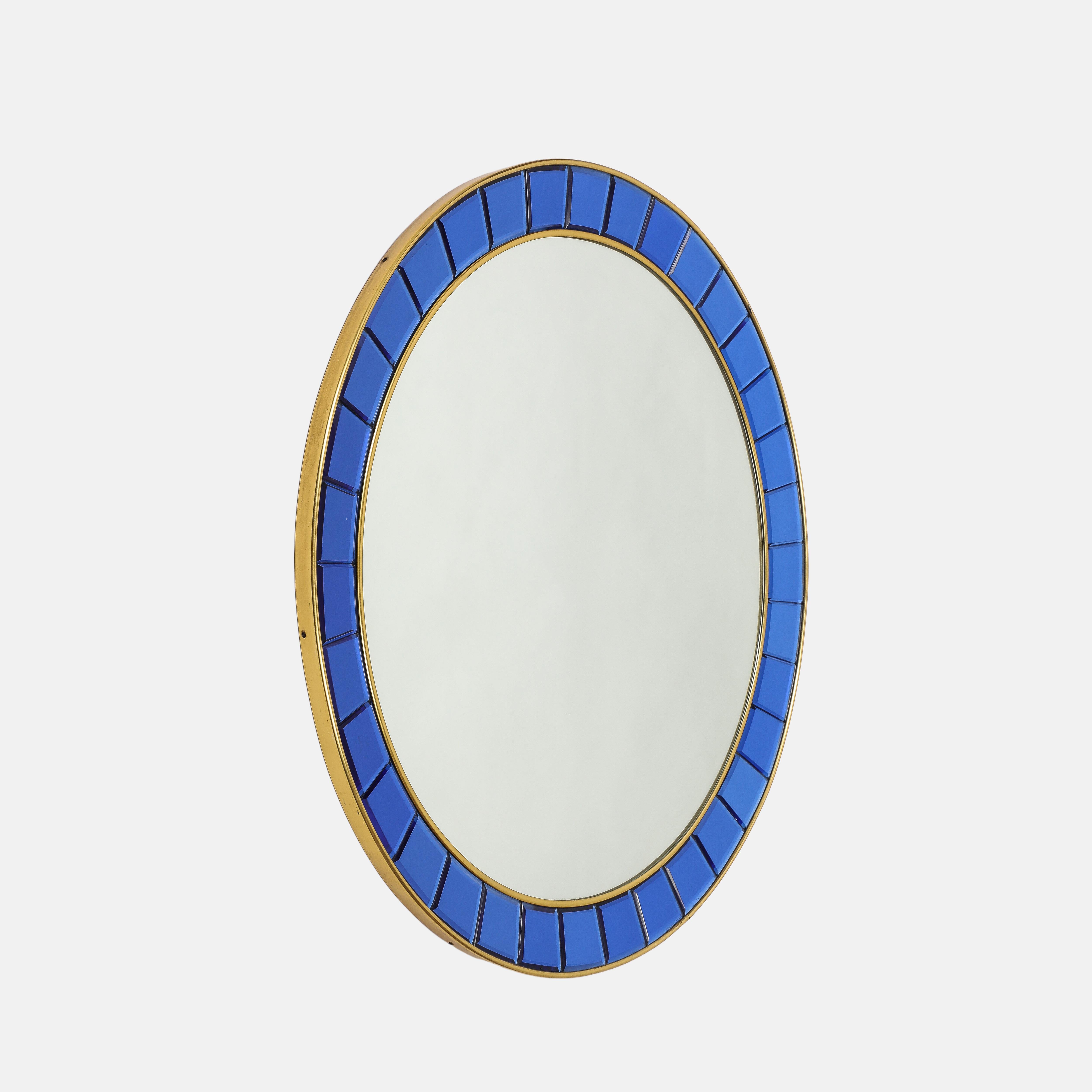Cristal Arte importante y elegante gran espejo circular modelo 2679 con piezas de cristal azul biselado talladas a mano y enmarcadas por bordes de latón dorado y cristal de espejo sobre un soporte de madera. El color azul intenso del cristal