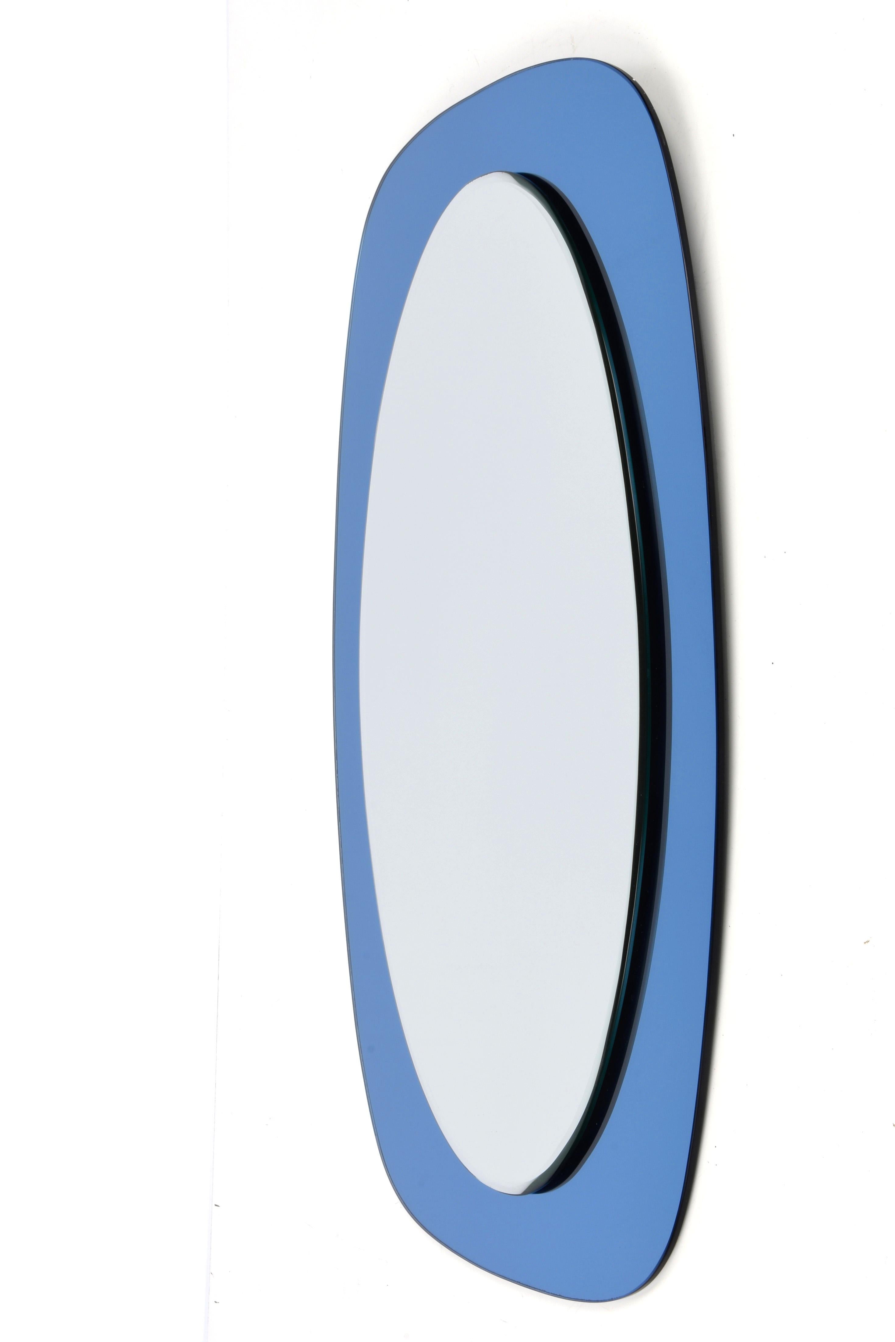 Amazing oval double-leveled midcentury mirror with a blue glass frame. This wonderful piece was produced in Italy during the 1960s and it is attributed to crystal Art.

In its essential and pure mid-century design and lines, this marvellous item