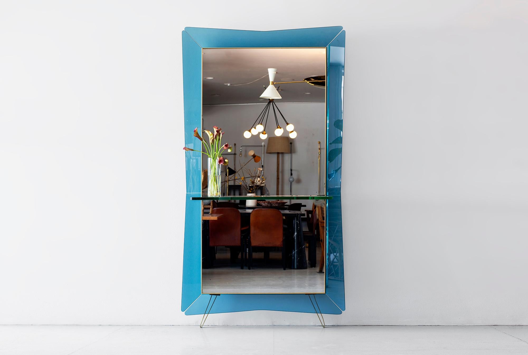 Giant Cristal art mirror with blue frame and glass console.
Brass loop legs.