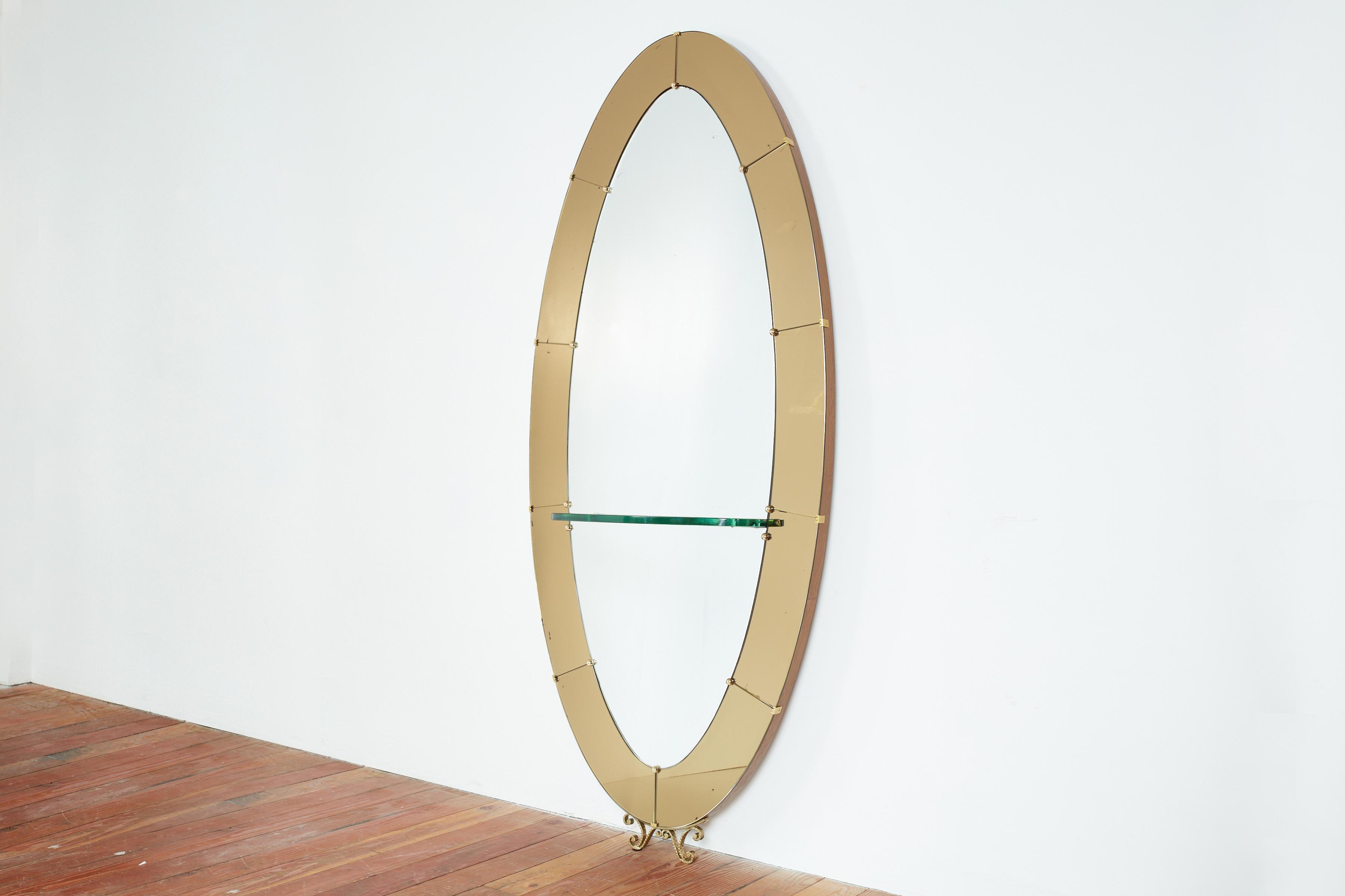 Gorgeous large Cristal Art wall mirror with shelf with gold yellow glass and decorative brass base.

Oval shape with original patina'd mirror and bright yellow gold colored glass encompassed in a walnut wood frame w/ brass. 

Italy 1950s.