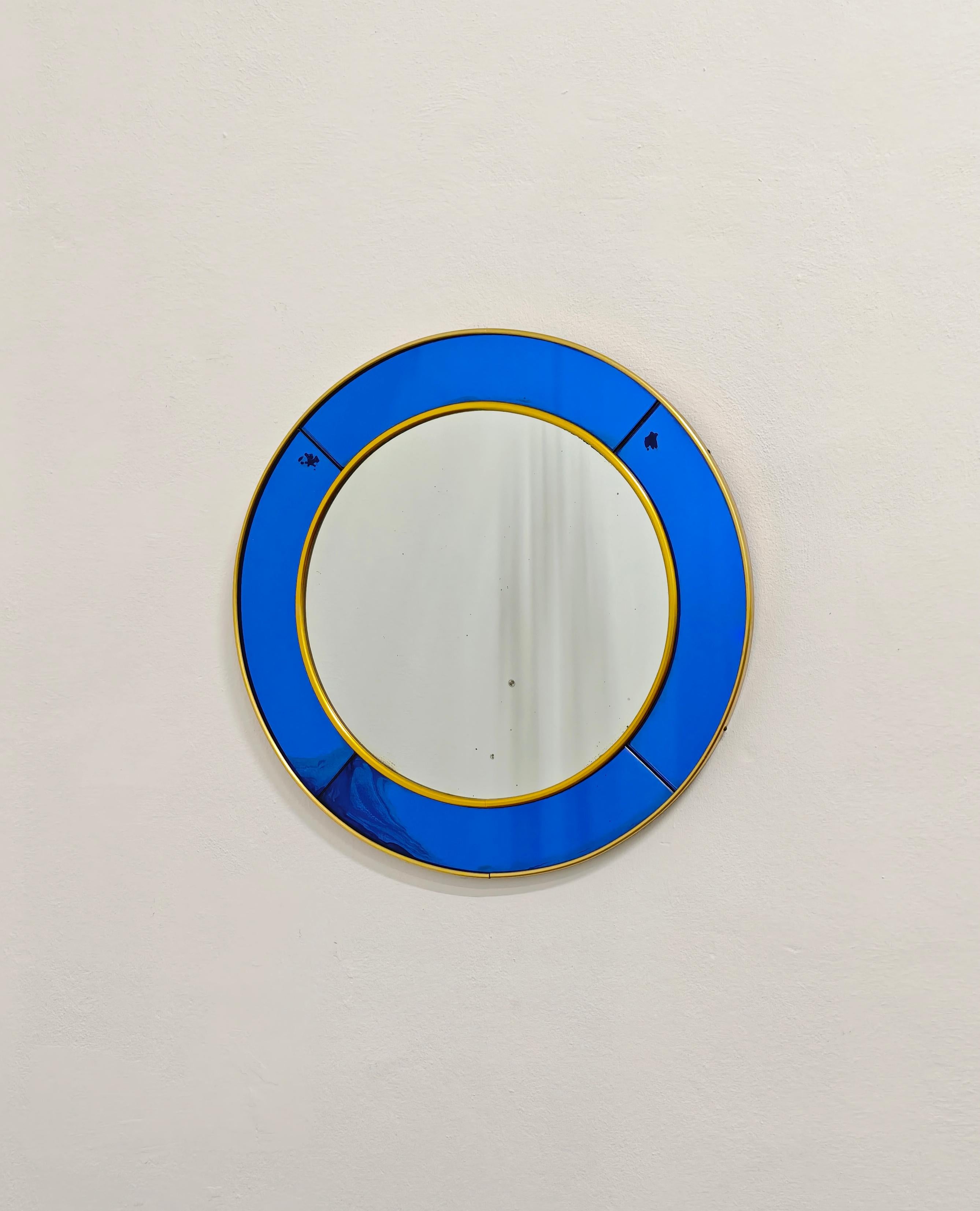 Espejo de pared circular de cristal azul y latón, fabricado por la empresa italiana Cristal Arte de Turín. Cristal Arte, empresa líder del sector del vidrio fundada en 1944 en Turín (Italia), está especializada en espejos y muebles de cristal.