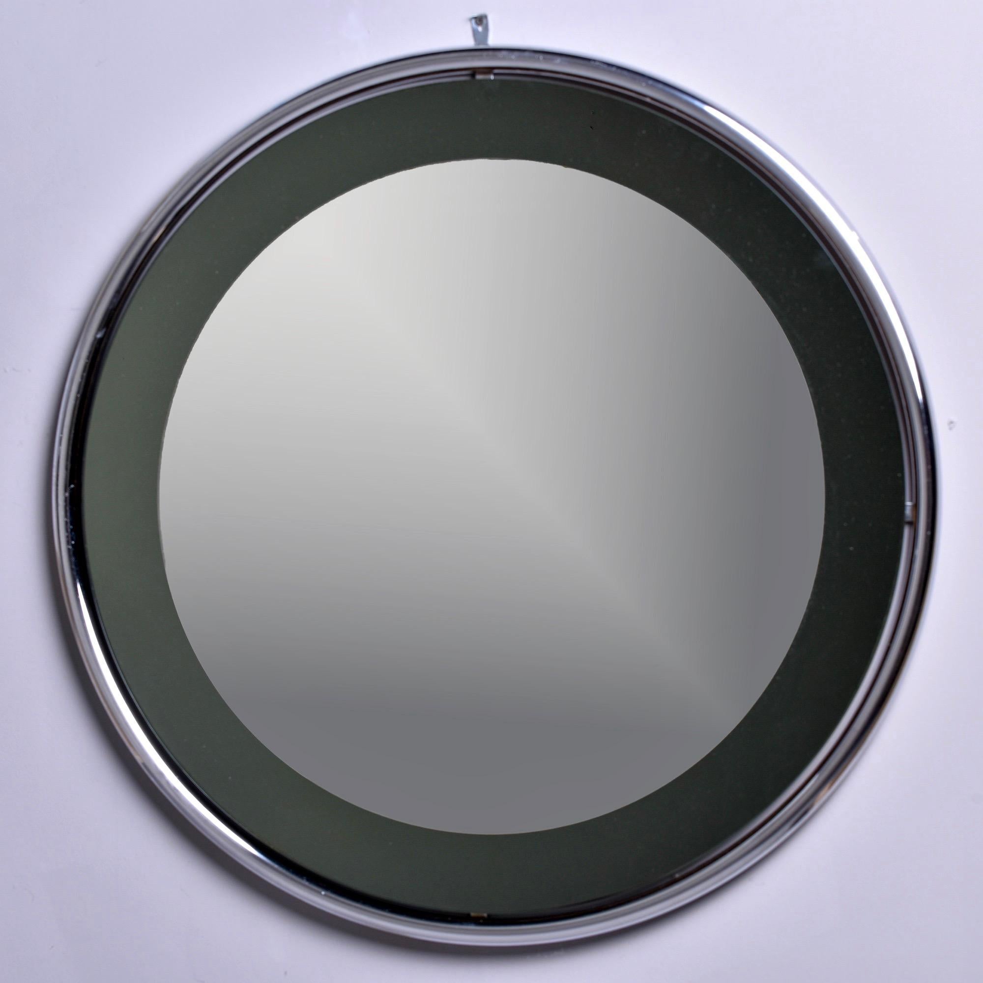 Circa 1960s mirror attributed to Italian maker Cristal Arte features a round, floating style chrome frame and smoke colored glass with a round mirror overlay. 

Very good overall vintage condition with minor scattered wear to chrome and some small