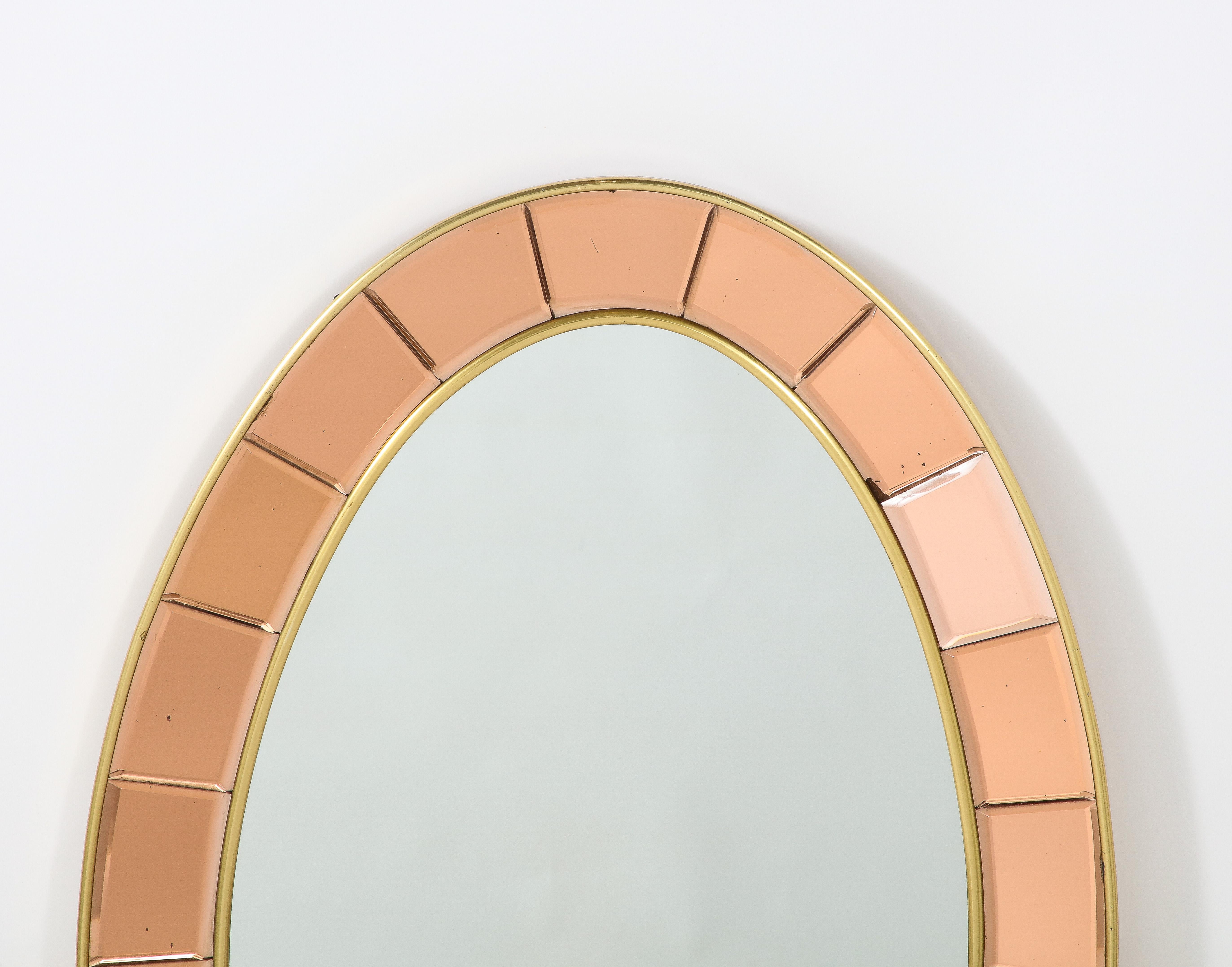 An exquisite Cristal Art oval mirror, the border defined with segmented and beveled hand-cut rose gold crystal glass and the inner oval frame with clear glass. The outer frames rose gold is a beautiful contrast with the warm gilt brass trim,