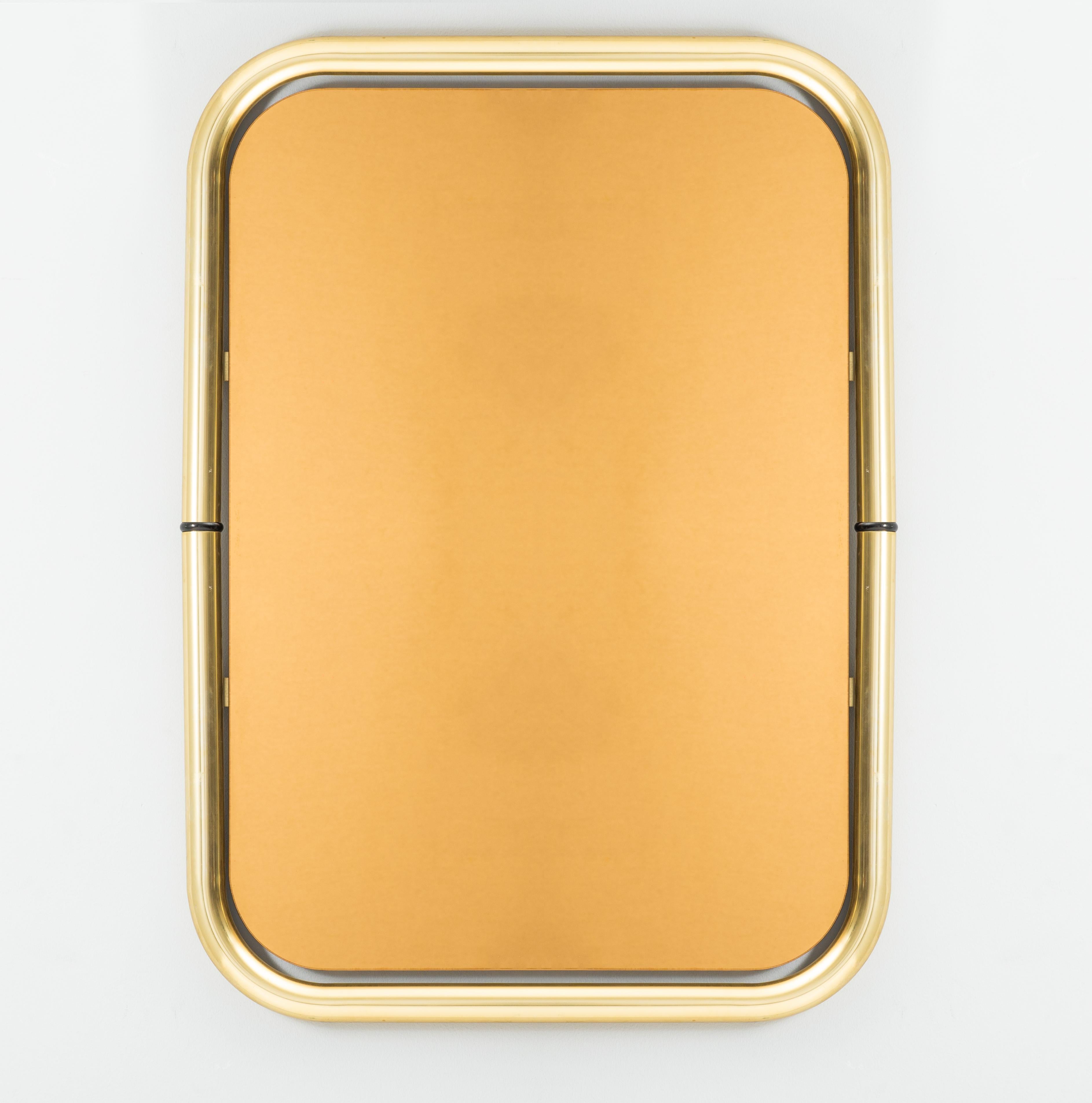 High-quality solid brass and pink glass wall mirror designed and manufactured in Italy in the 1970s by Cristal Arte. The brass is in original patina, the mirrored glass  rosy,bronzed effect. It is in good condition. 
A super example of space-age