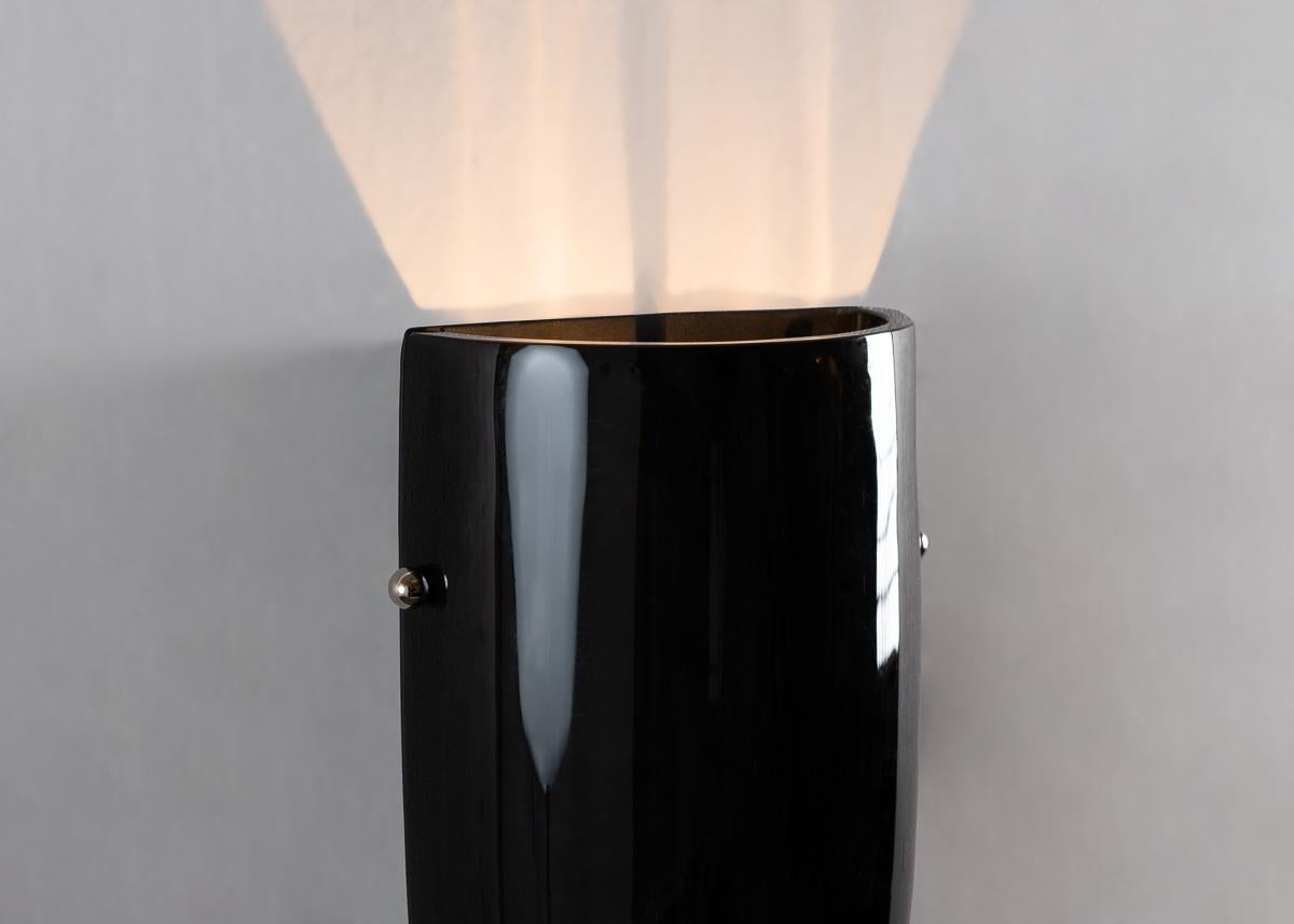 This elegant sconce's unique presence can be attributed to Benito's unique use of obsidian, a mineral stone 2-3 million years old, which diffuses light at its vertical seams, shooting the rest of it skyward, and reflecting that from without.
