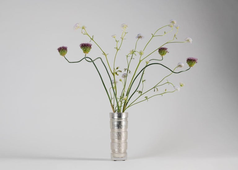 Silver is a banded cylindrical vase of faceted, frosted crystal, the many cuts of which make evident the generations of expertise accumulated by the illustrious French firm crystal Benito.