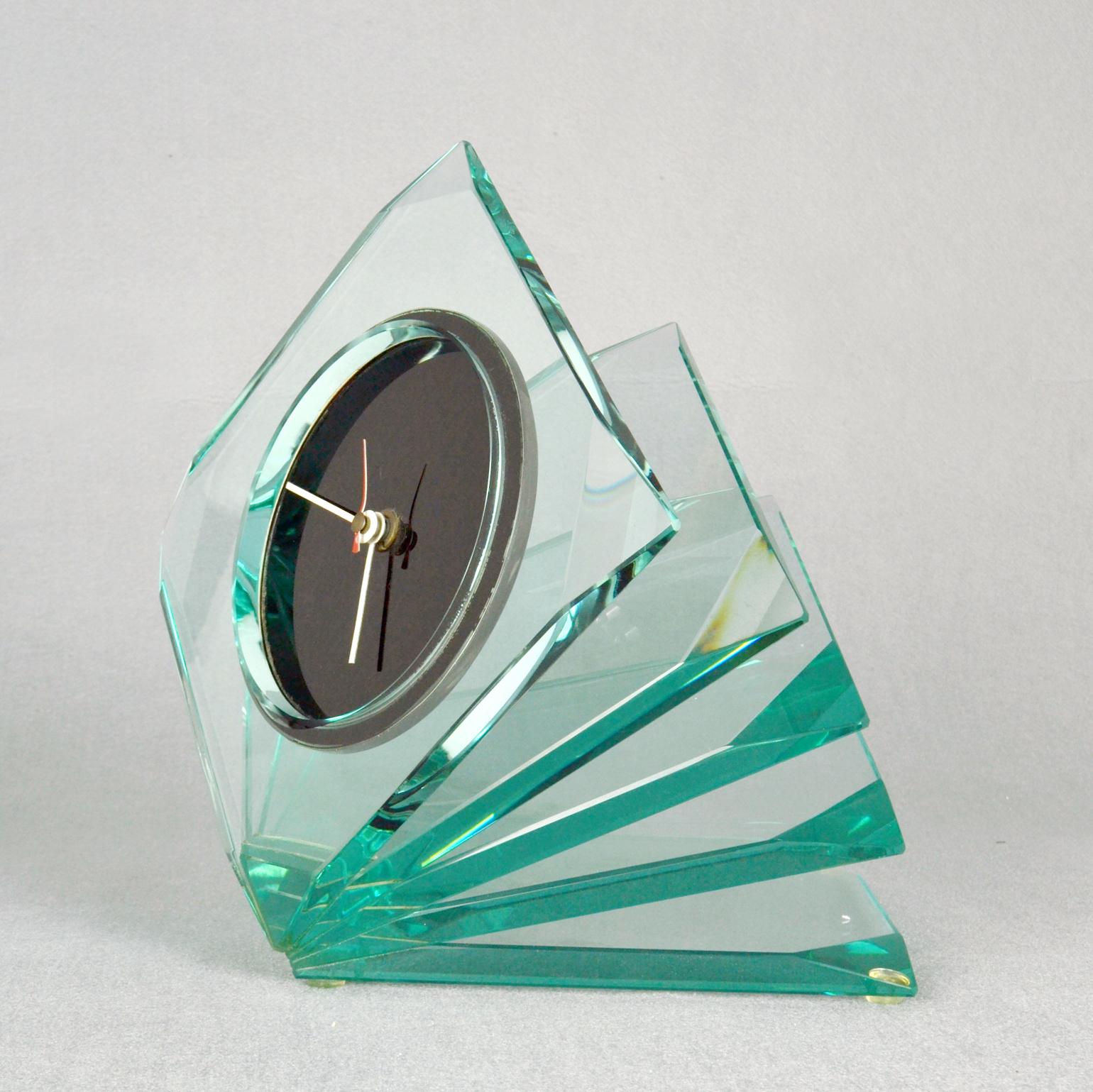 L'horloge en verre Cristal, attribuée à Fontana Arte, Italie, années 1970, est composée de 5 segments de verre finement taillés et soudés entre eux. Ils sont positionnés comme un ventilateur dans une direction ascendante. L'horloge est alimentée par