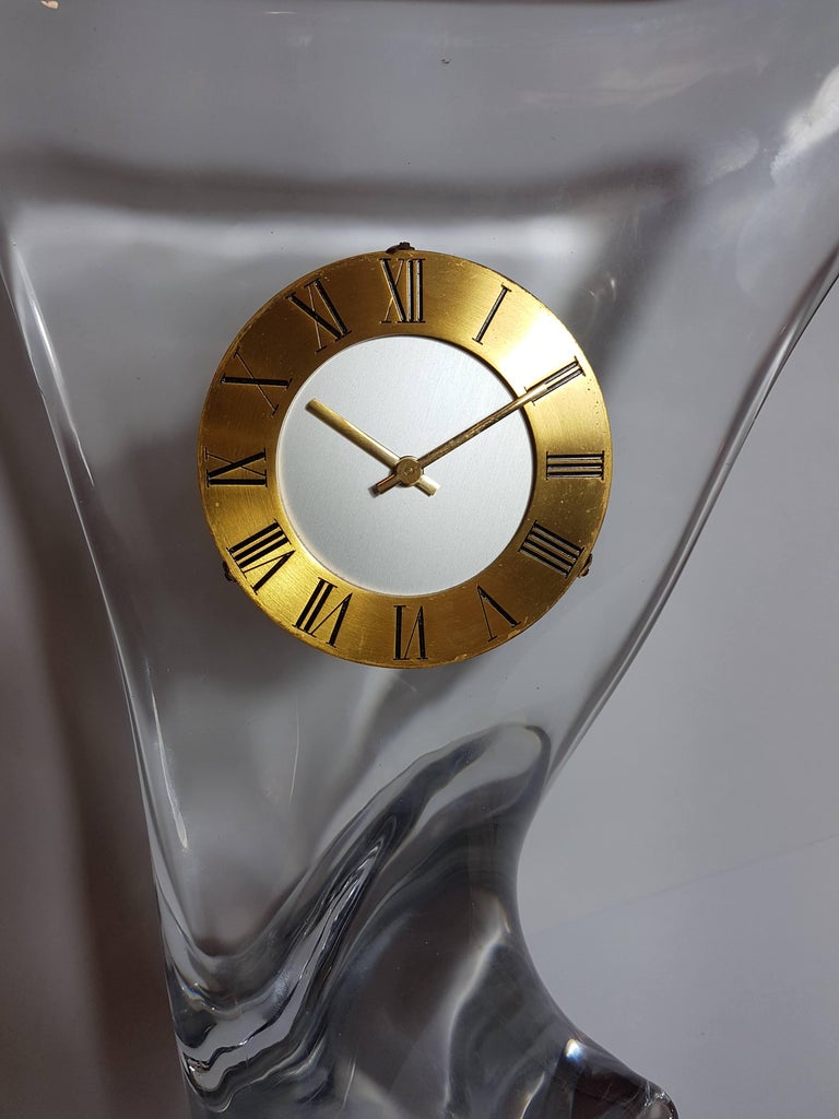 Stunning midcentury crystal table clock by Cristalleries Schneider. Biomorphic shape crystal, round dial with golden brass edge, Roman numbers and sword-shaped hands. Mechanical movement.
