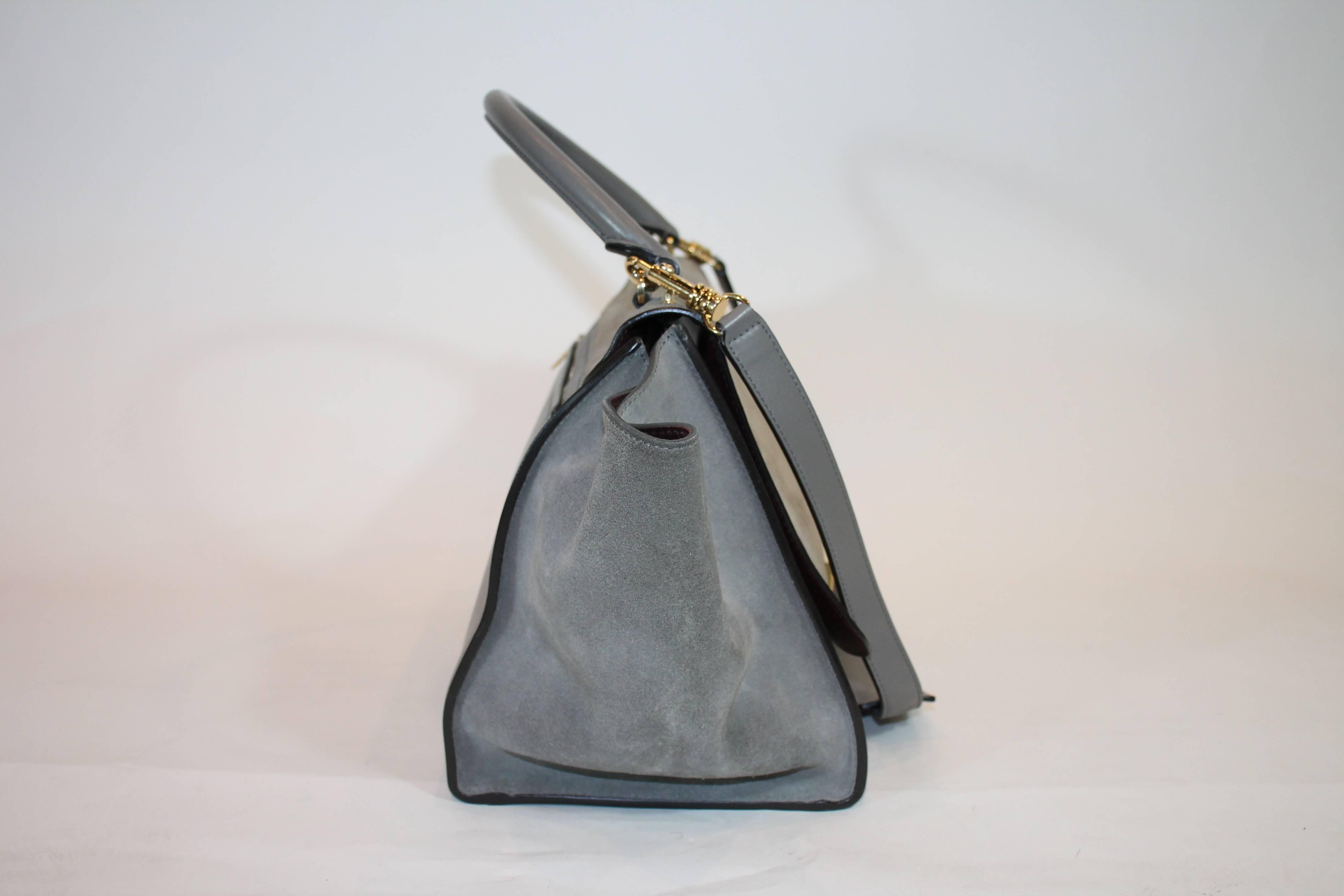 Nubuck. Gold-tone hardware. Zip closure at top featuring flip-lock closure at front flap. Grey smooth leather trim throughout. Single rolled top handle. Tonal suede panels at side gussets. Two interior opened pockets. From 2012 Collection. Estimated