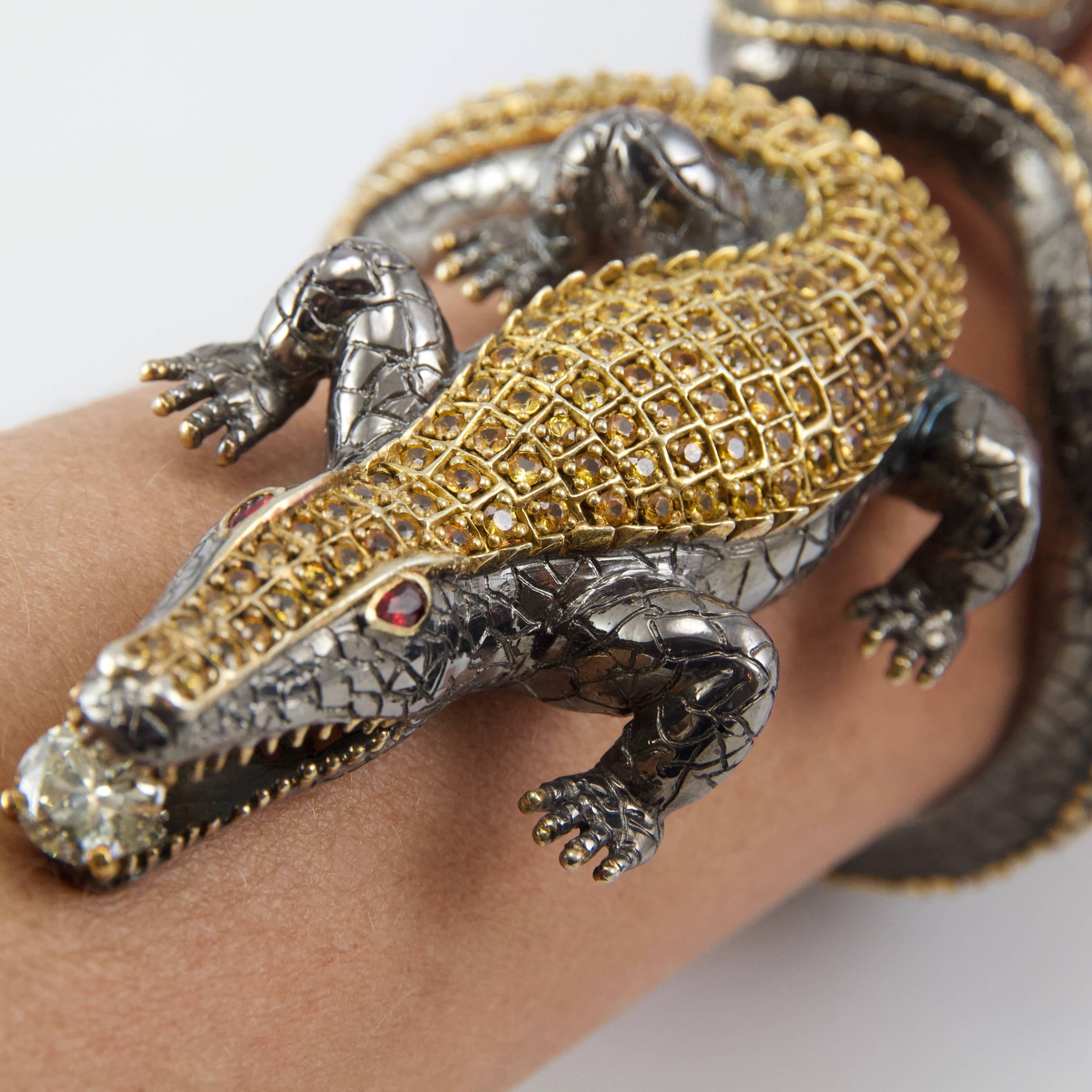Terrific crocodile bangle in silver and vermeil, set on the back with yellow sapphires, eyes in rubies, crunching a large demi-taille diamond weight almost 3.5 carats. 
Contemporain work  by Christophe Terzian, french creator. 
