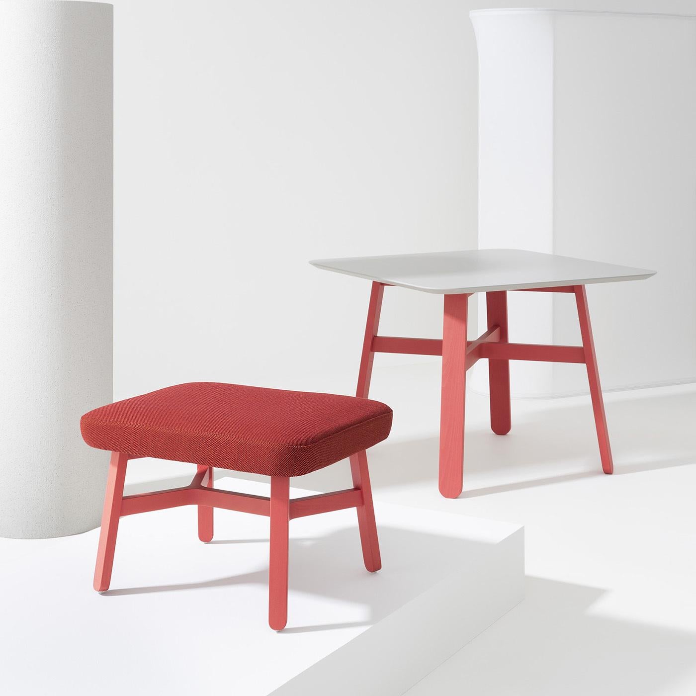 Brimming with stylish flair, this ottoman designed by Emilio Nanni will bring a lively pop of color to any interior. Its sleek silhouette is fashioned of beech tinted in a bright shade of red, with flattened, slightly slanted legs supporting the